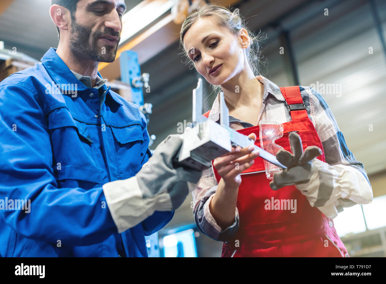 Frau und Mann Arbeiter Kontrolle Messungen von Metall Werkstück Stockfoto