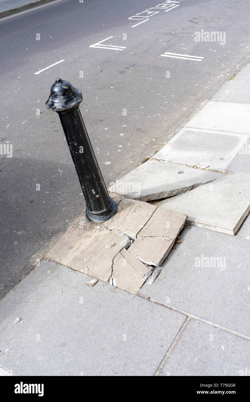 Defekter Bürgersteig Stolpergefahr und Metall Poller Stockfoto