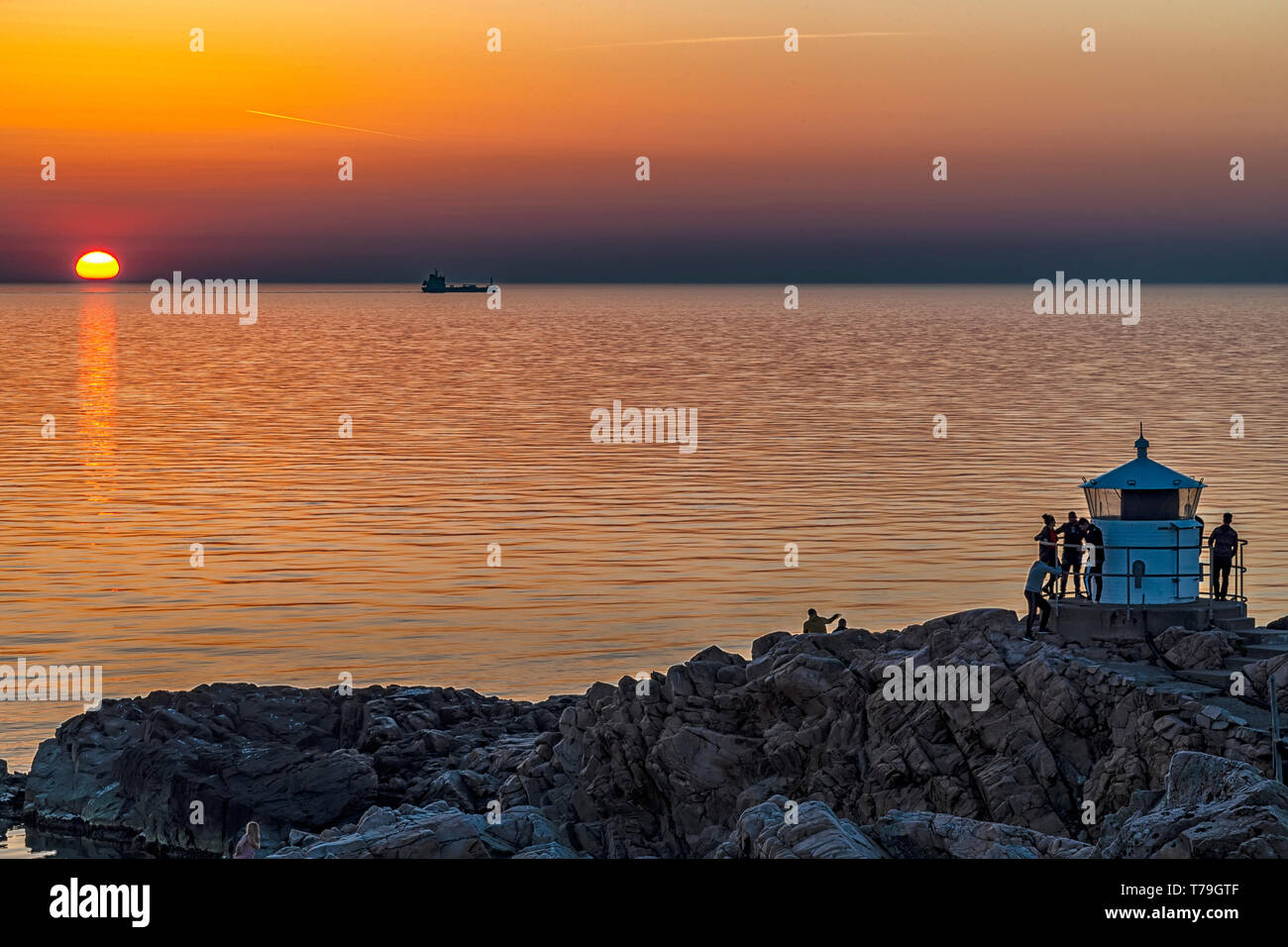 Eine Gruppe von Menschen versammeln sich an einem der Leuchttürme bei Sonnenuntergang von Süd Schweden Küstenregion der Kullaberg. Stockfoto