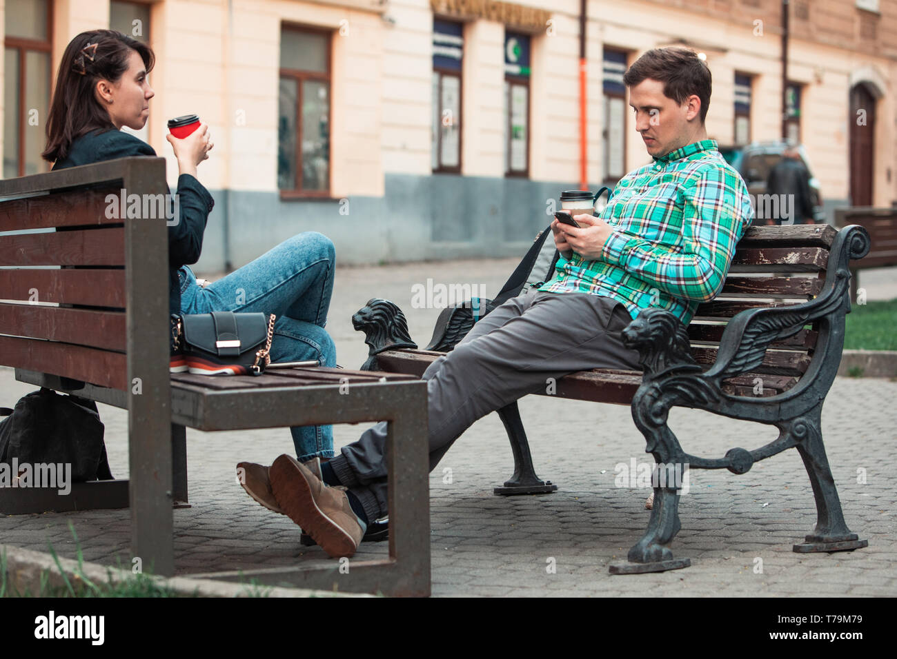 Kommunikationsproblem Mann mit Frau sitzt auf der Bank an der Strasse der Stadt trinken Kaffee im Pappbecher suchen in Telefone. lifestyle Konzept. schüchtern zu sprechen Stockfoto