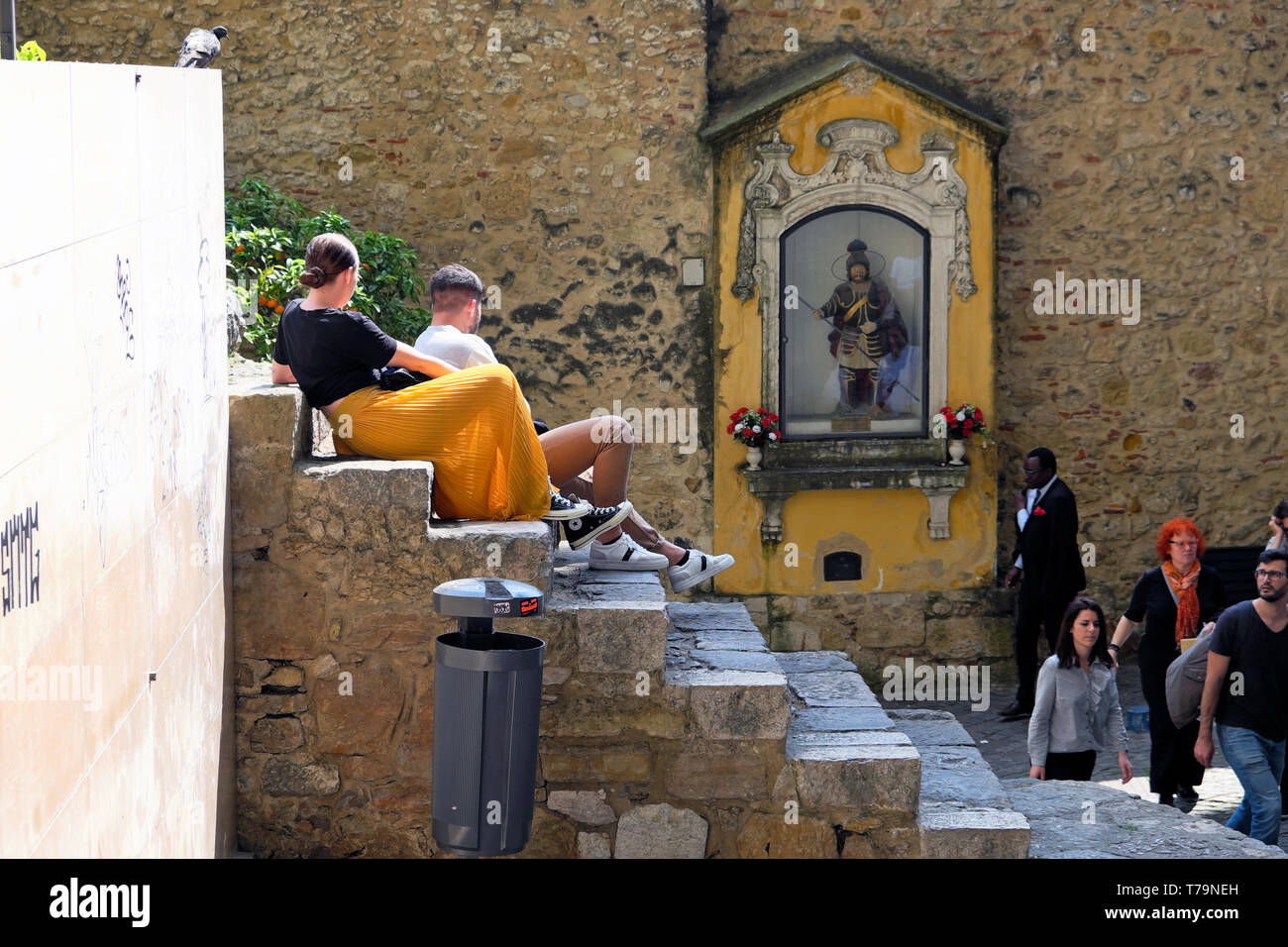 Touristen sitzen auf Schritte, die von der Statue von St. George, das Heiligtum am Eingang Castelo de Sao Jorge in Lissabon Schloss in Lissabon Portugal Europa EU-KATHY DEWITT Stockfoto