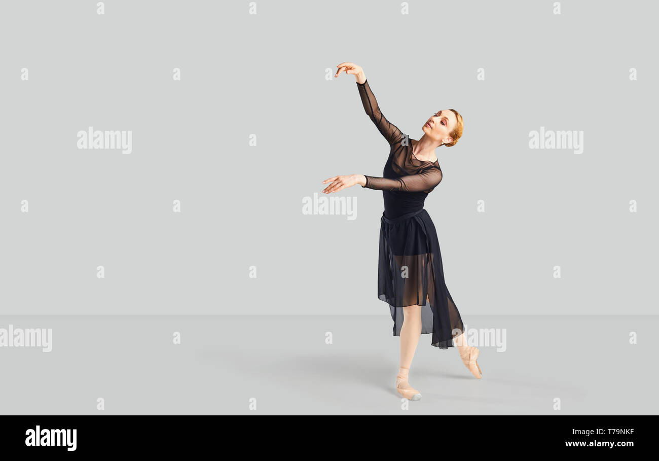 Ballerina Tänzerin in schwarzem Kleid auf einem grauen Hintergrund. Stockfoto