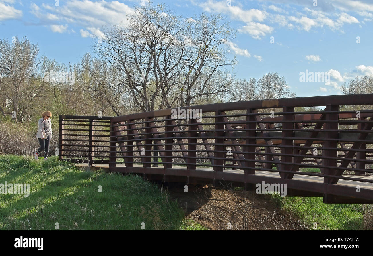 Aurora, Colorado - Mai 3, 2019: Schöne Landschaft mit Fußgängerbrücke in der kleinen Nachbarschaft Park, lokale Frau auf der Brücke. Stockfoto