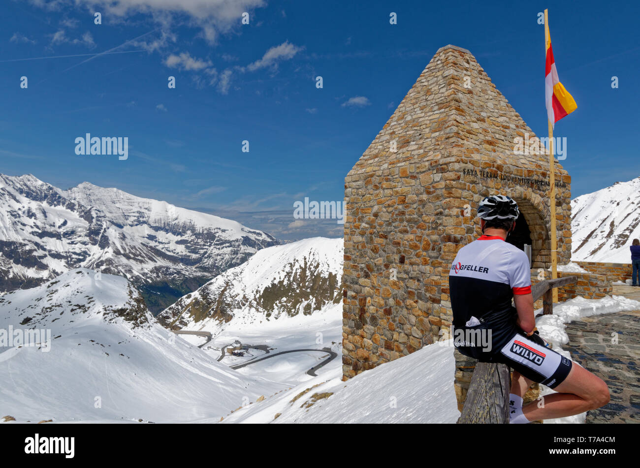 Radfahrer auf eine kurvenreiche Straße und die schneebedeckten Berge aus dem Fuscher Torl auf der Großglockner Hochalpenstraße, Österreich Stockfoto