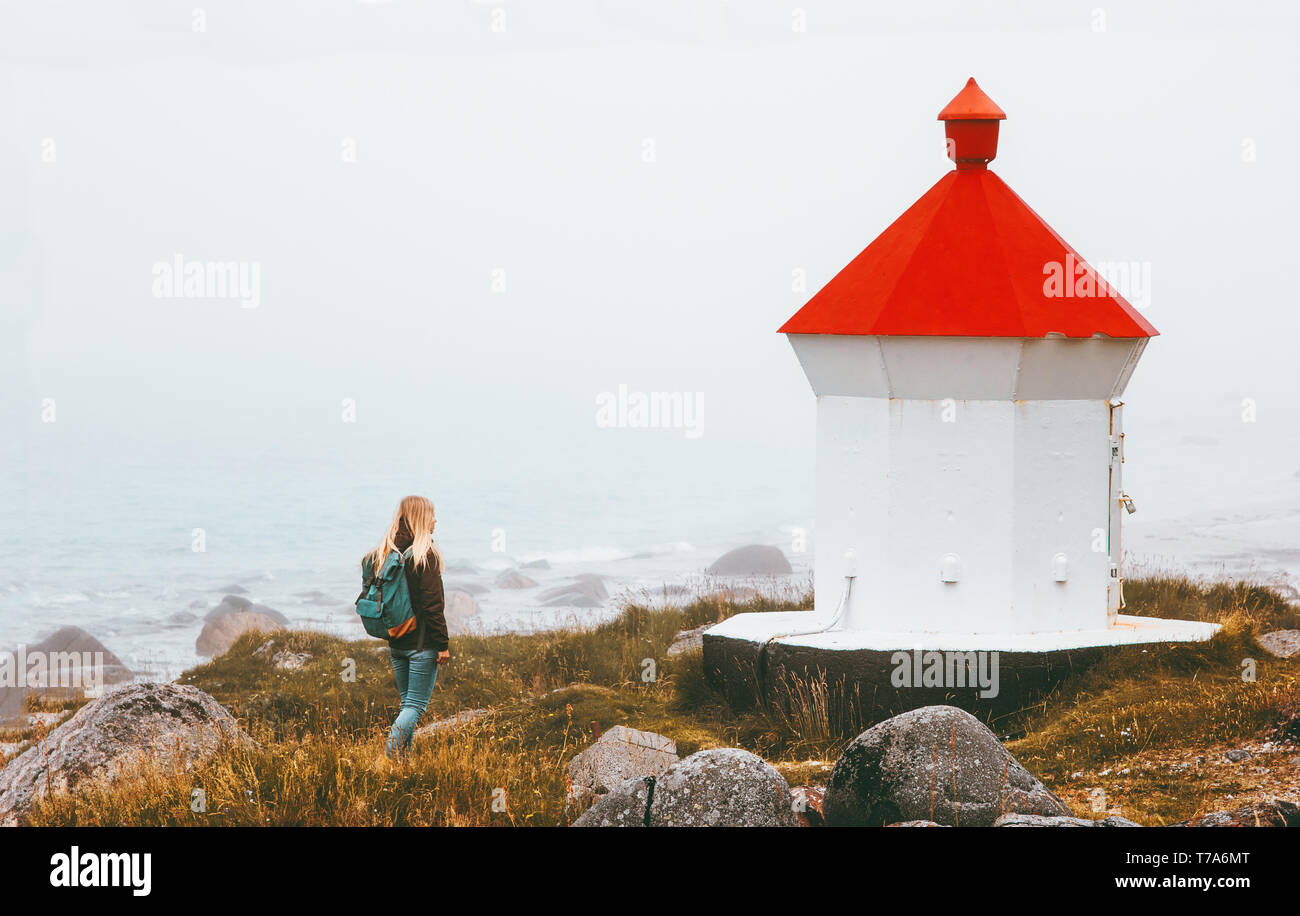 Frau gehen mit Leuchtturm nebligen Meer solo Reisen lifestyle Abenteuer skandinavischen Reise outdoor Stockfoto