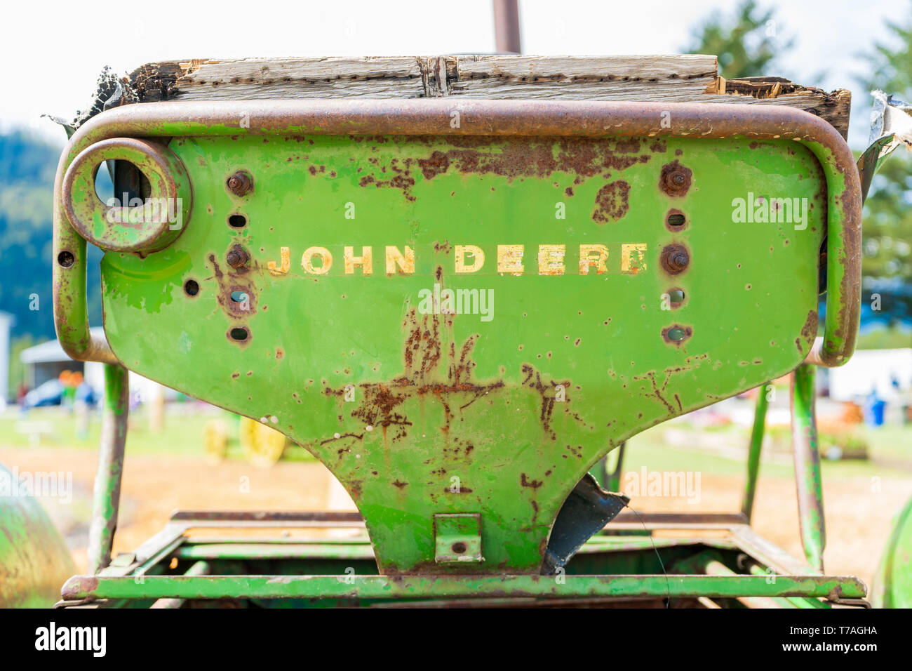 Alte, rostige John Deere Traktor Sitz, mit der Wortmarke Logo auf dem Rücken, abgenutzt. Classic John Deere Bild von einem antiquierten Traktor oder Bauernhof ausstatten Stockfoto
