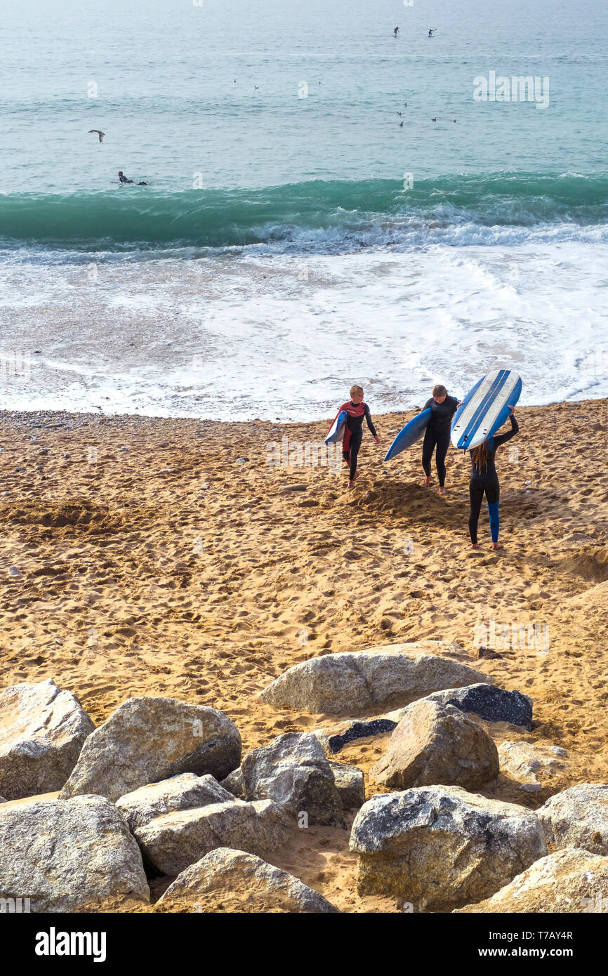 Die jungen Surfer, die ihre Surfbretter und zu Fuß unterwegs das Meer auf den Fistral Beach in Newquay in Cornwall. Stockfoto