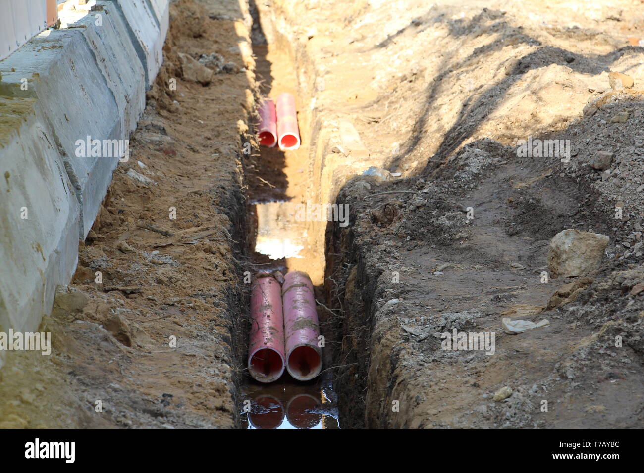 Rohre für warmes und kaltes Wasser. In den Graben sind Kunststoffrohre. Rohrleitungsbau. Es gibt keine Menschen. Stockfoto