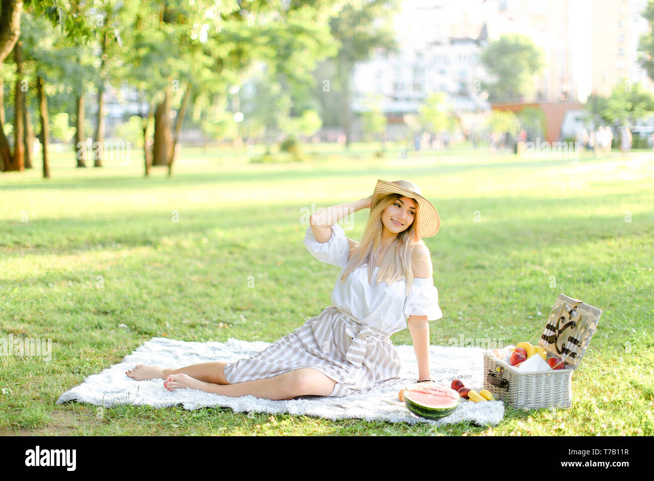 Junge aucasian Frau im Park sitzen auf Plaid in der Nähe von Obst, Gras im Hintergrund. Stockfoto