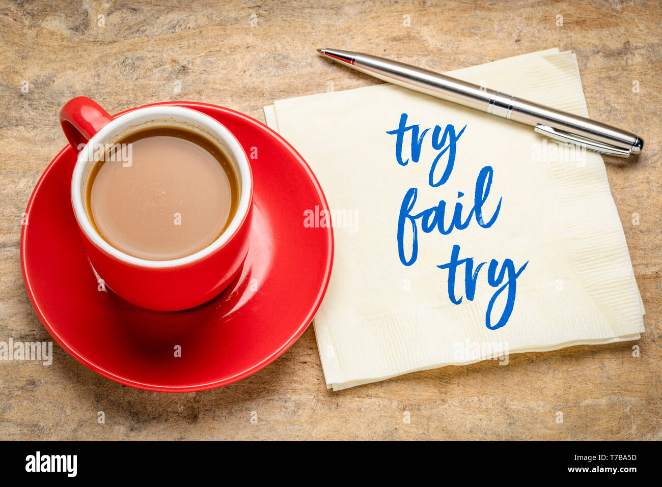 Versuchen Sie es, und versuchen Sie erneut, die Konzept-Handschrift auf Serviette mit einer Tasse Kaffee Stockfoto