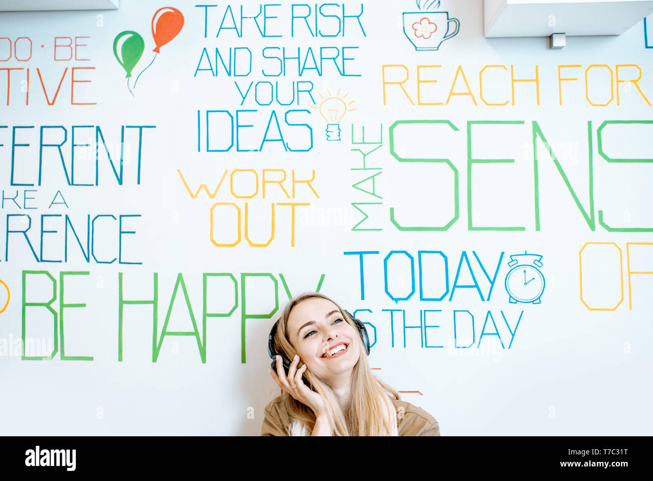 Portrait einer jungen lächelnde Frau mit Kopfhörer an der Wand Hintergrund mit verschiedenen Inschriften auf das Thema der psychischen Gesundheit Stockfoto