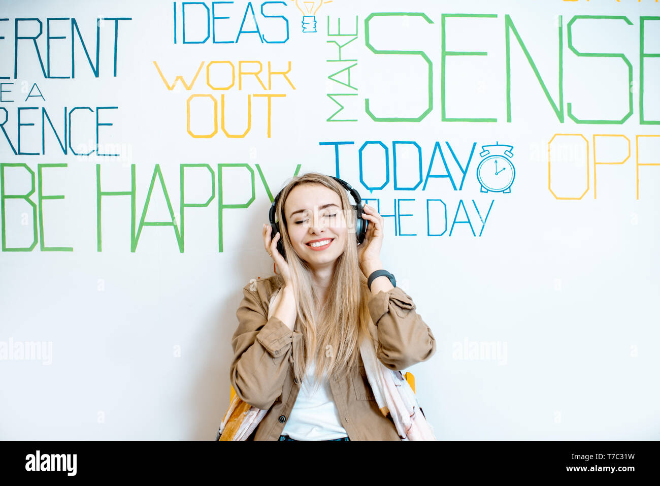 Portrait einer jungen lächelnde Frau mit Kopfhörer an der Wand Hintergrund mit verschiedenen Inschriften auf das Thema der psychischen Gesundheit Stockfoto