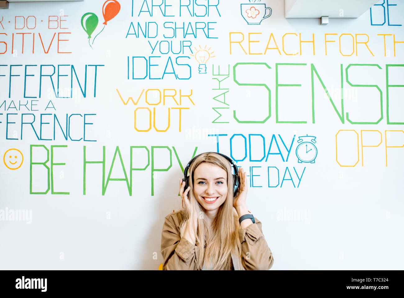 Portrait einer jungen lächelnde Frau mit Kopfhörer an der Wand Hintergrund mit verschiedenen Inschriften auf das Thema der psychischen Gesundheit Stockfoto