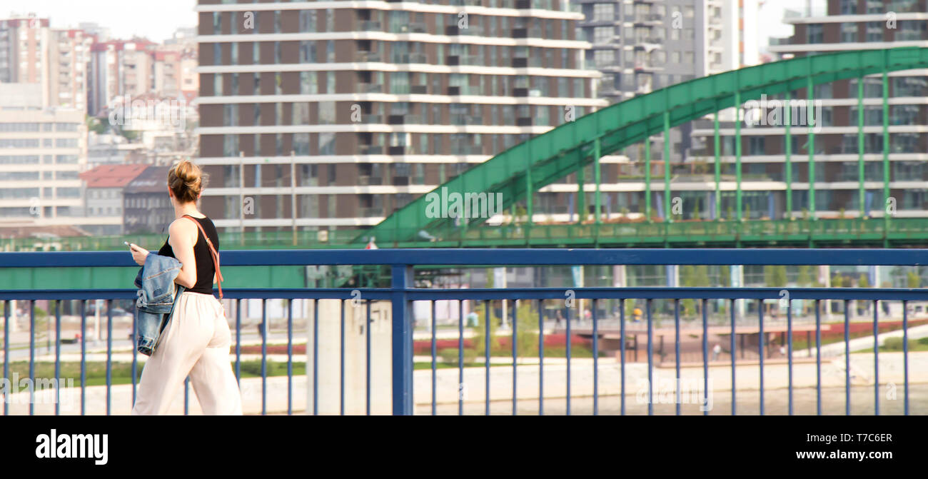 Belgrad, Serbien - April 26, 2019: Junge Frau zu Fuß über die Brücke mit Blick auf Belgrad Waterfront Projekt Stockfoto