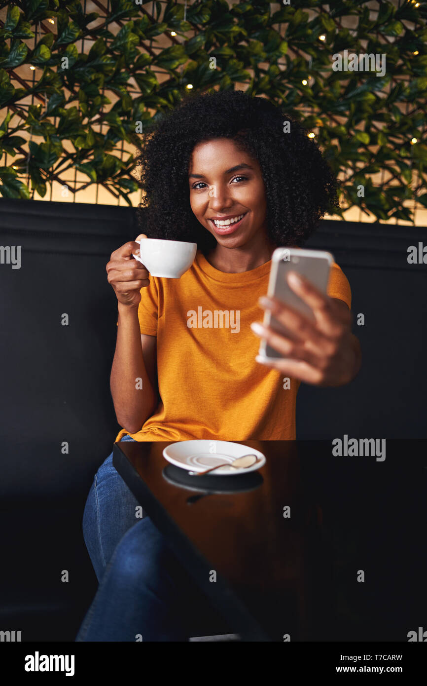 Eine attraktive Lächelnden jungen Frau unter selfie auf Handy im Cafe Stockfoto