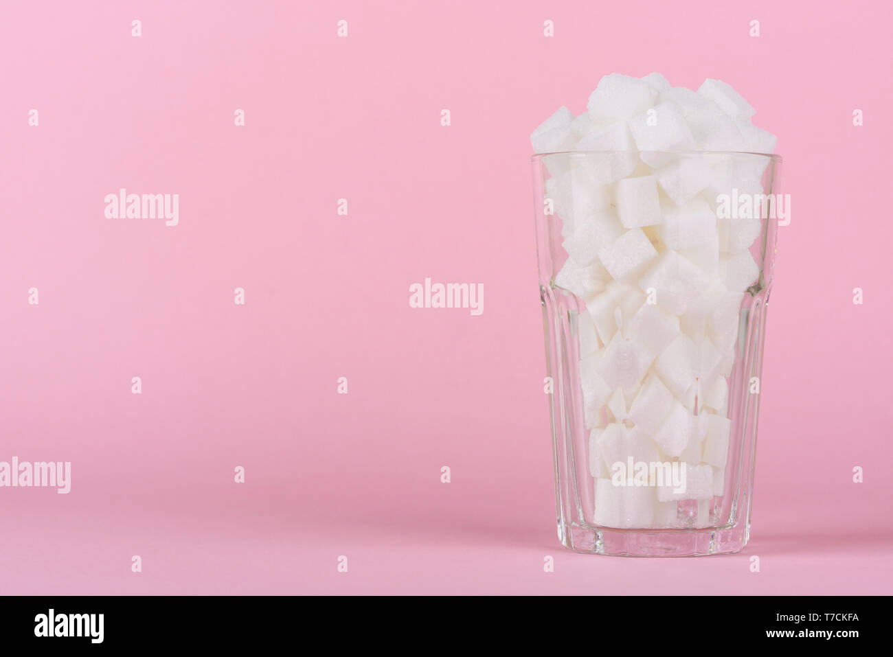 Trinken Glas von Pauschalbeträgen Würfelzucker auf Rosa pastell Hintergrund. Unhealthly Ernährung mit süßen zuckerhaltigen Softdrinks Konzept. Stockfoto