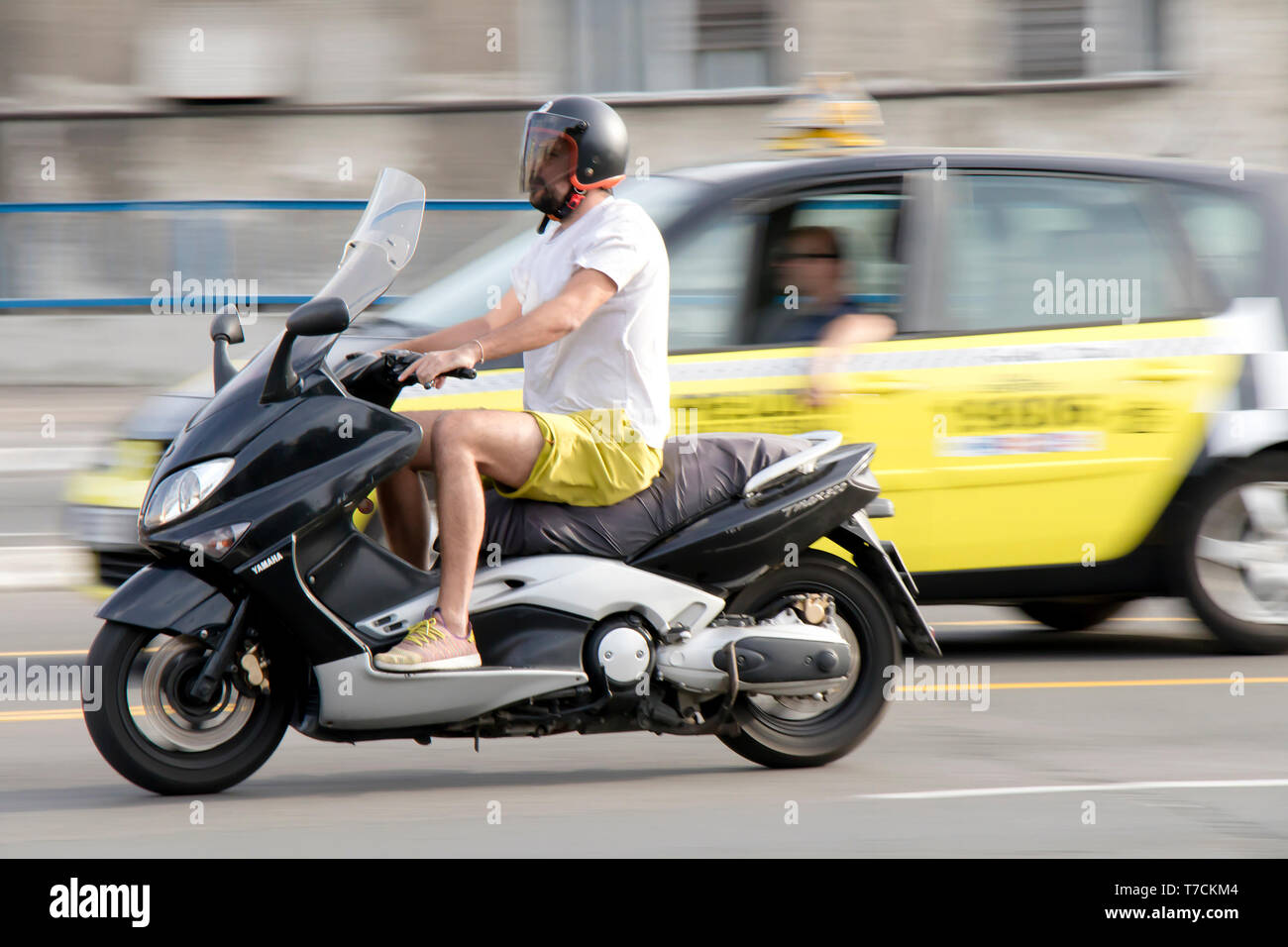 Belgrad, Serbien - April 26, 2019: Ein Mann reiten Roller in Stadt Straße Verkehr und blurry Taxi Auto hinter Stockfoto