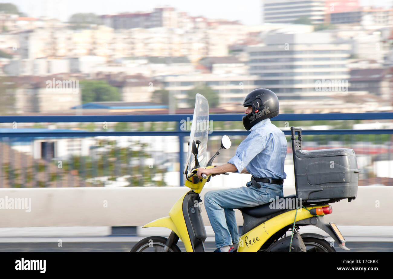 Belgrad, Serbien - 26. April 2019: reifer Mann reiten sein retro Scooter auf Stadt Straße Brücke mit verschwommenen hellen Stadtlandschaft Hintergrund Stockfoto