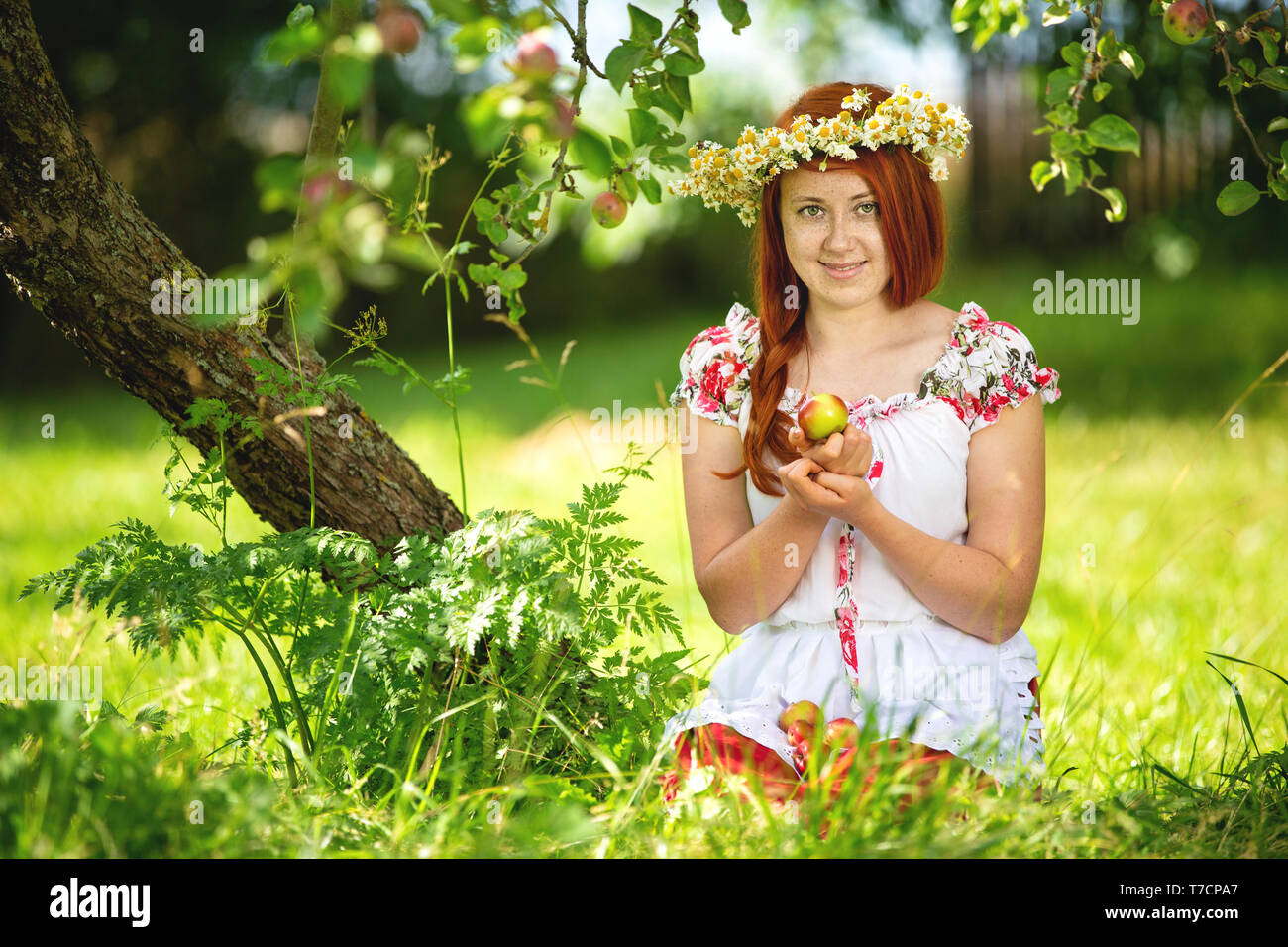 Ländliche Mädchen im traditionellen Outfit im Apple tree Stockfoto