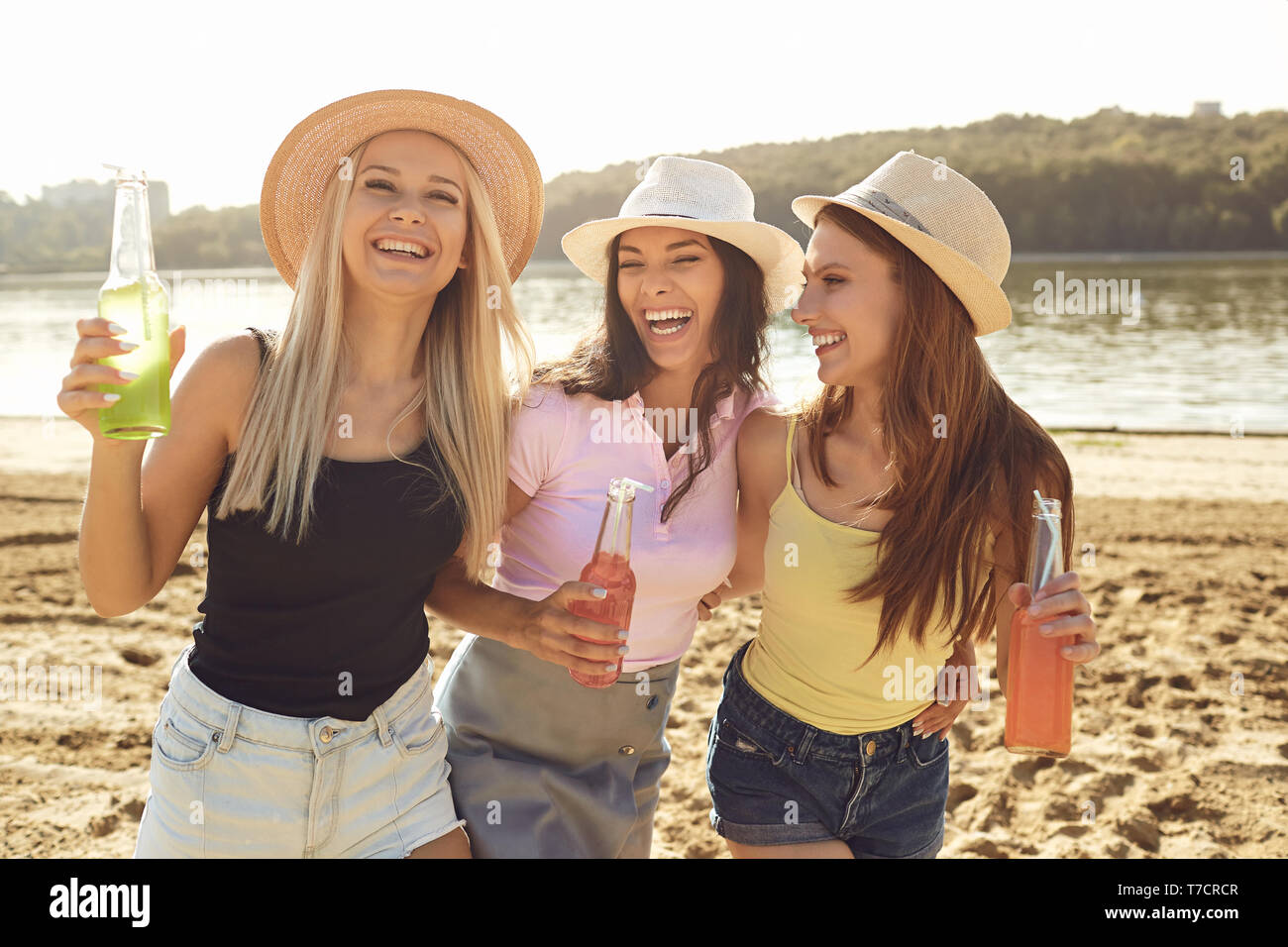 Junge lachen Freundinnen Getränke am Strand Stockfoto