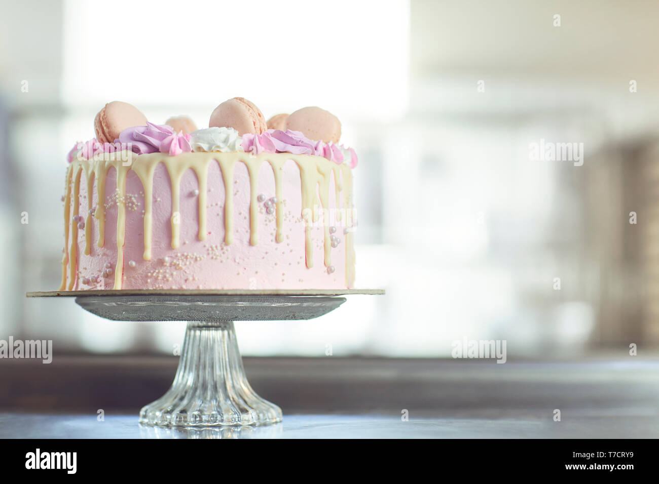 Rosa Kuchen mit Makronen auf dem Tisch eingerichtet. Stockfoto
