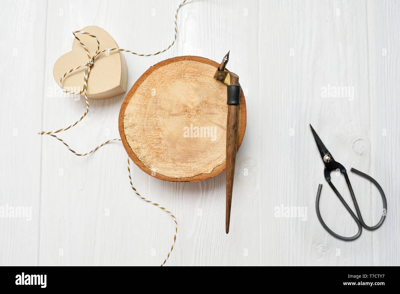 Kalligrafische Feder, liegt in der Nähe eines Holz- Kreis mit weißem Papier Herzen. Grußkarte für Valentines Tag mit Platz für Ihren Text. Flach, oben vie Stockfoto