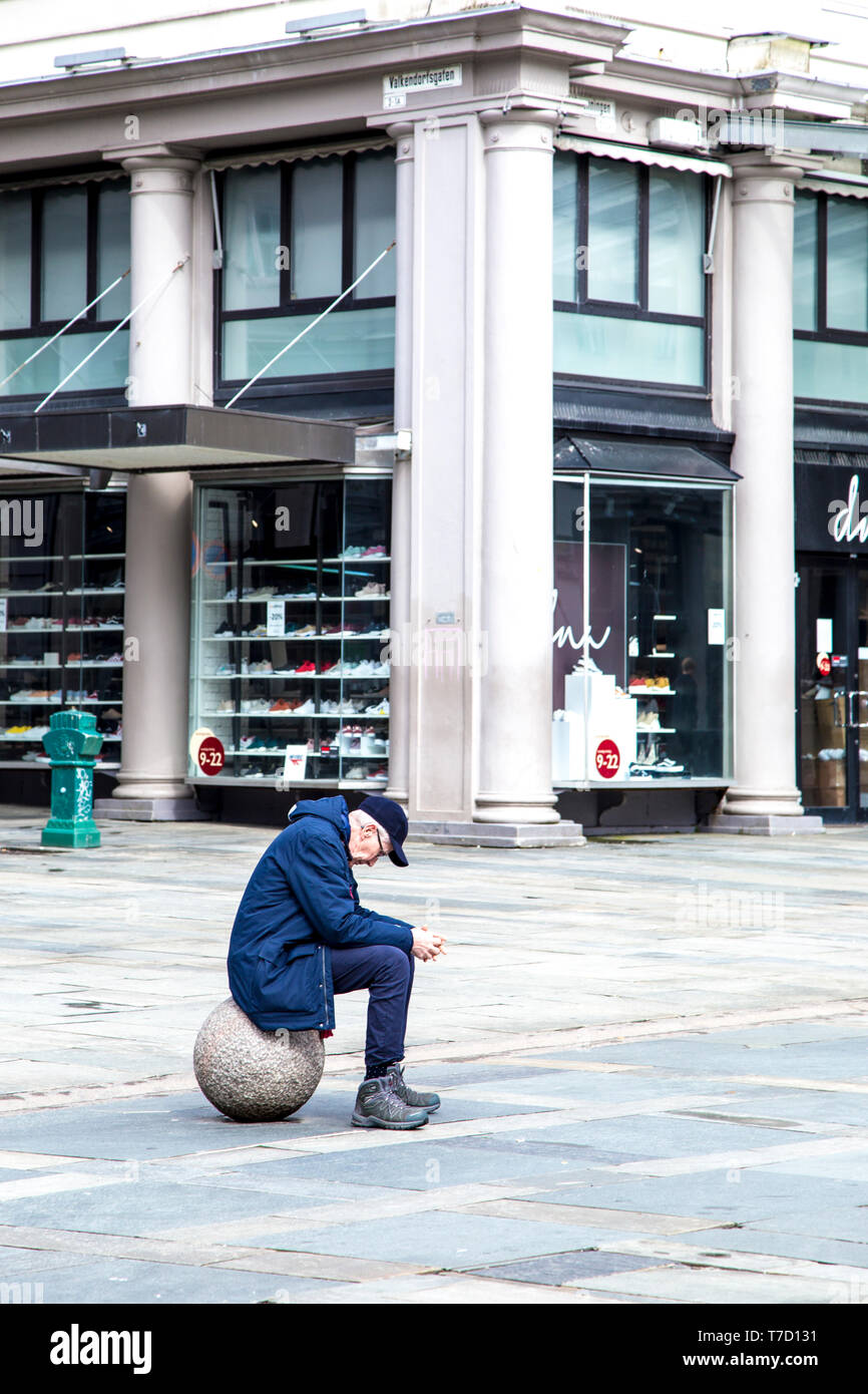 Traurige einsame Mann sitzt auf einem Ball in einer Stadt Stockfoto
