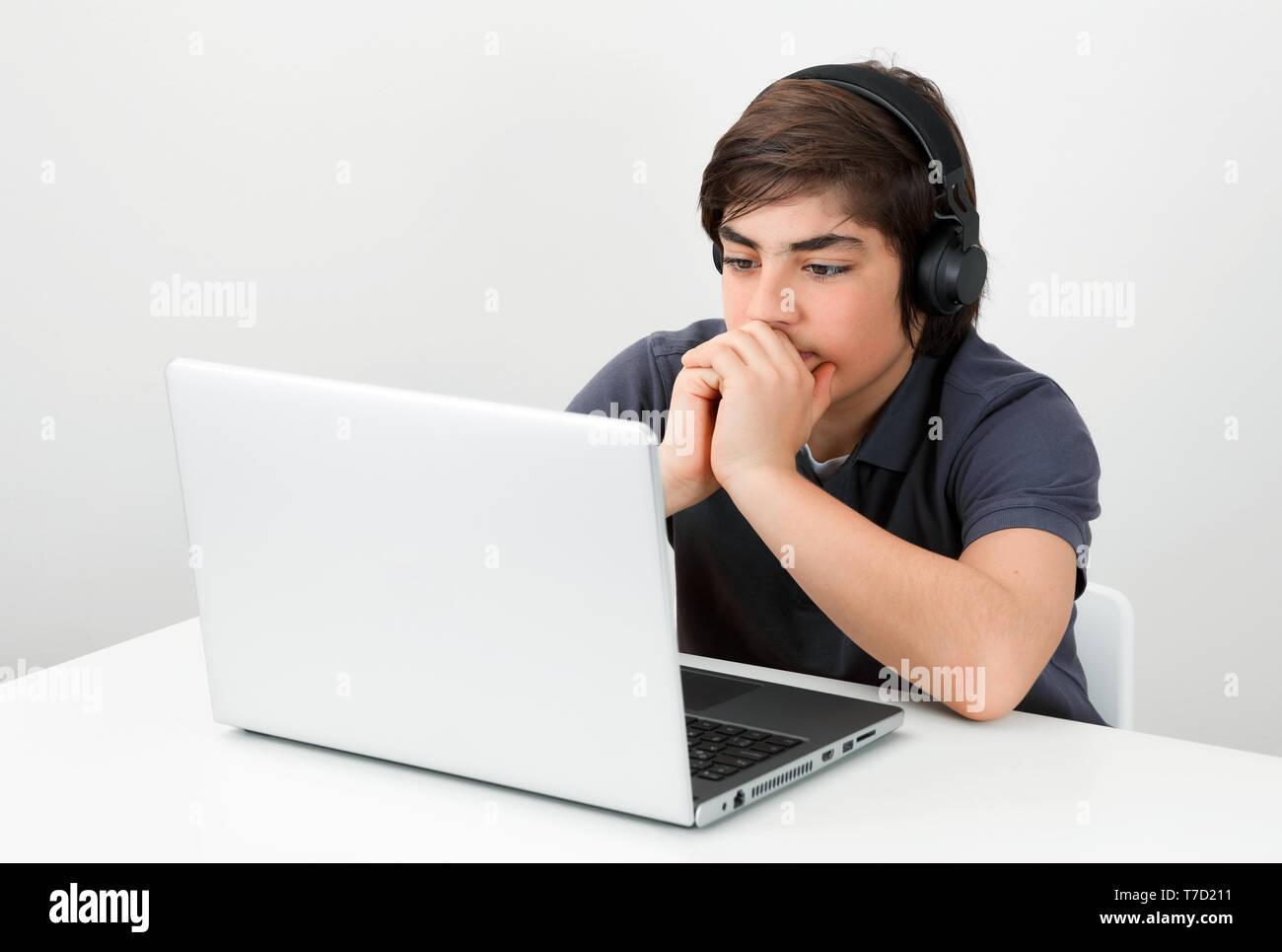 Kaukasische Teenager tragen die drahtlosen Kopfhörer am Schreibtisch auf dem Laptop Bildschirm schaut. Konzept moderner Bildung. Stockfoto
