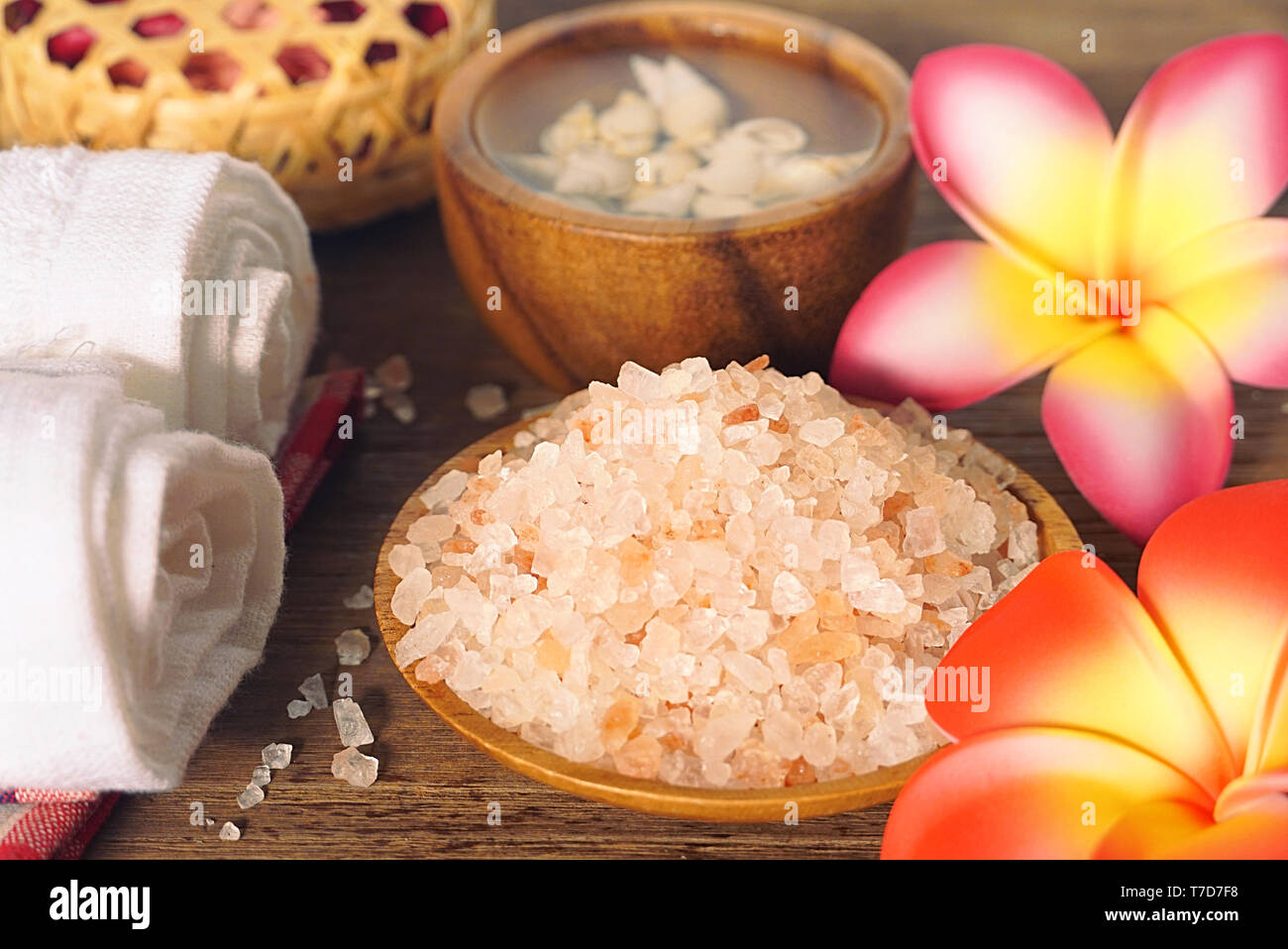 Close up Himalaya Salz mit Handtuch und Aroma Kerze verzieren mit trockenen Rosen auf Holz Tisch für Peeling spa Therapie. Stockfoto