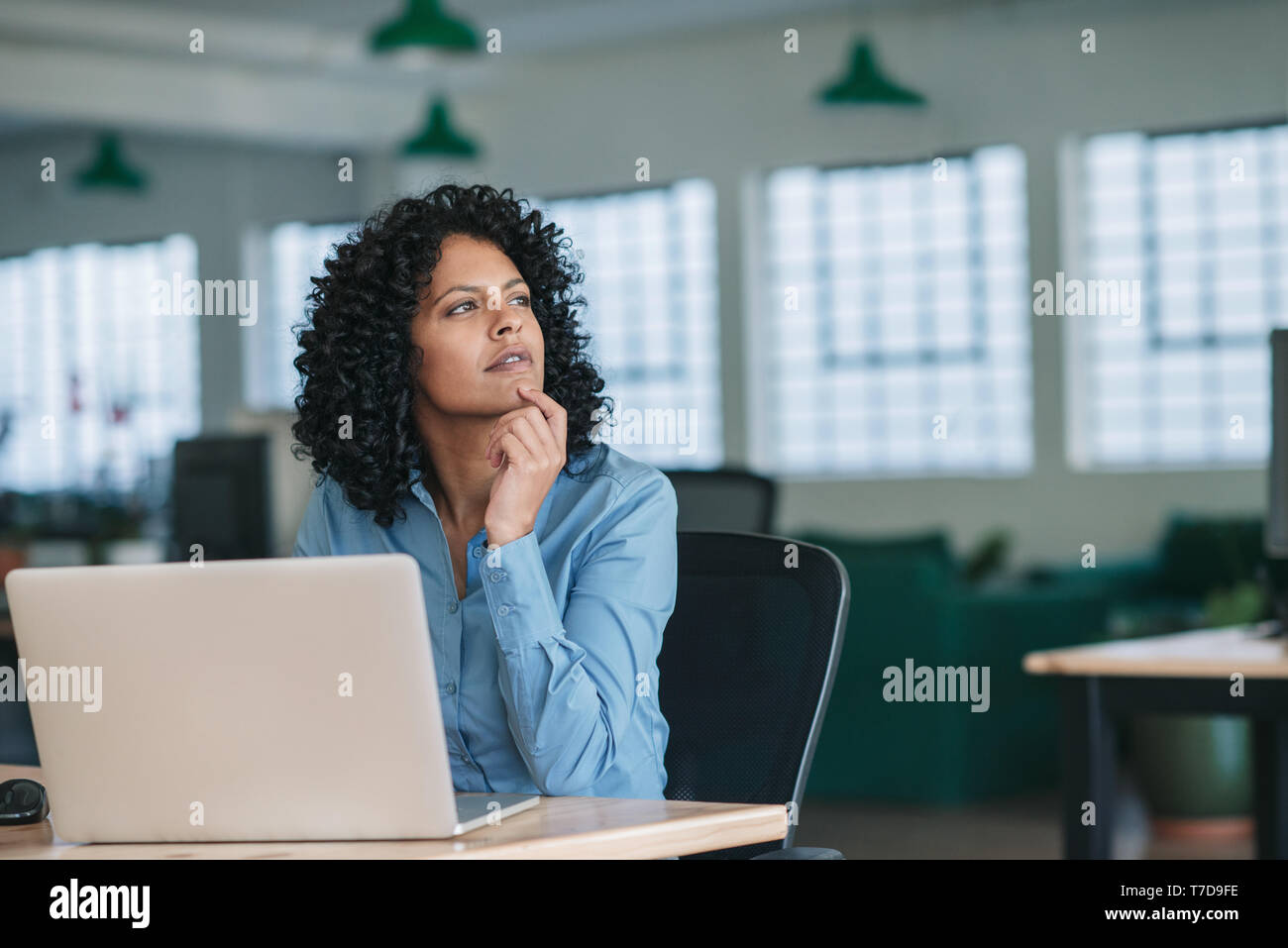 Junge Geschäftsfrau zu denken, während Sie mit einem Laptop bei der Arbeit Stockfoto