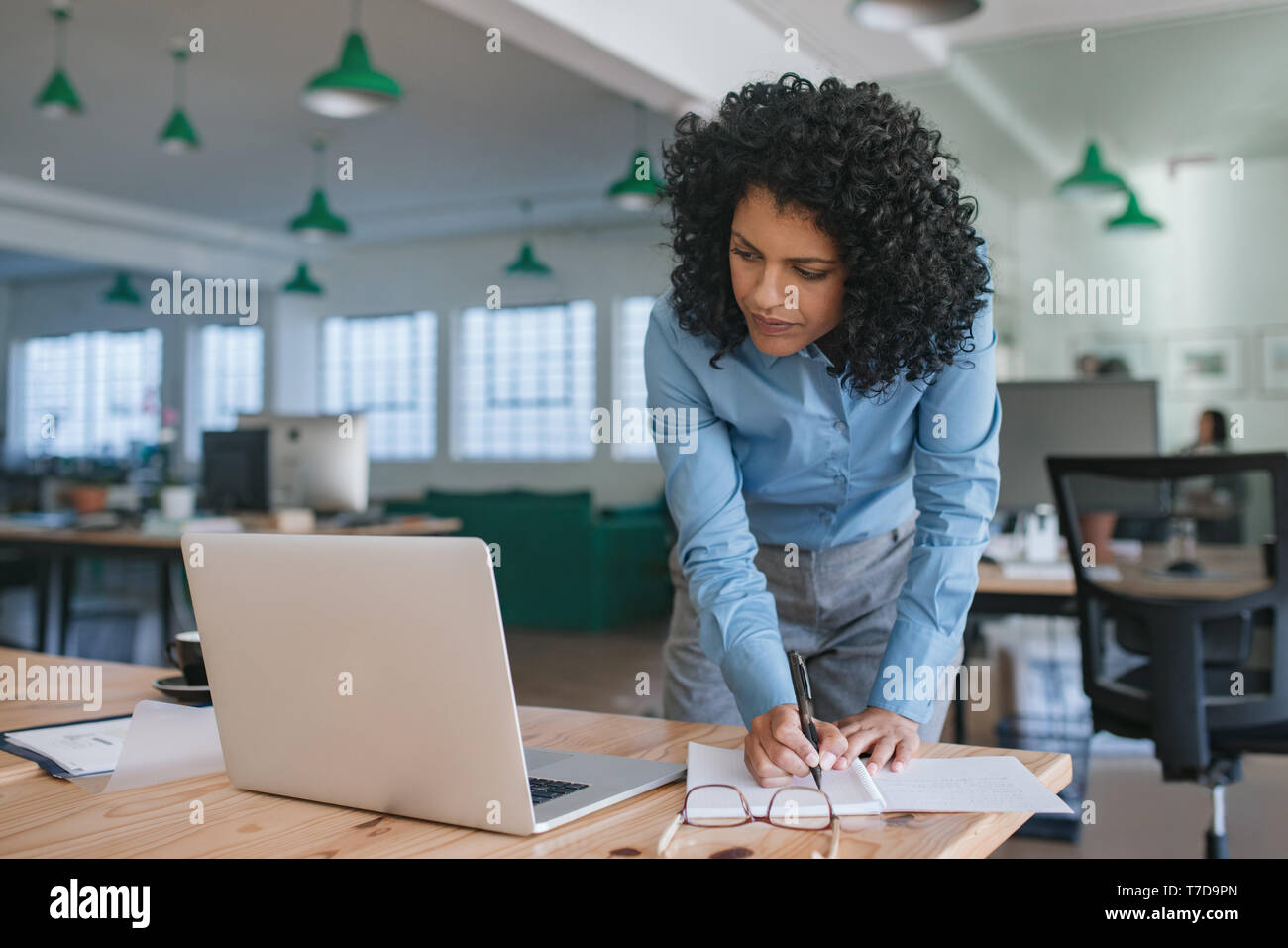 Im Mittelpunkt stehen junge geschäftsfrau in Ihrem Büro Schreibtisch Schreiben von Notizen Stockfoto