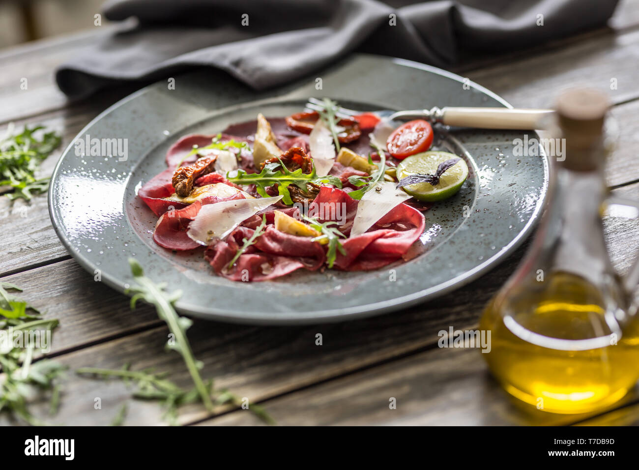 Carpaccio vom Rind auf Platte mit getrockneten Tomaten Artischocken Rucola und Parmesan Stockfoto