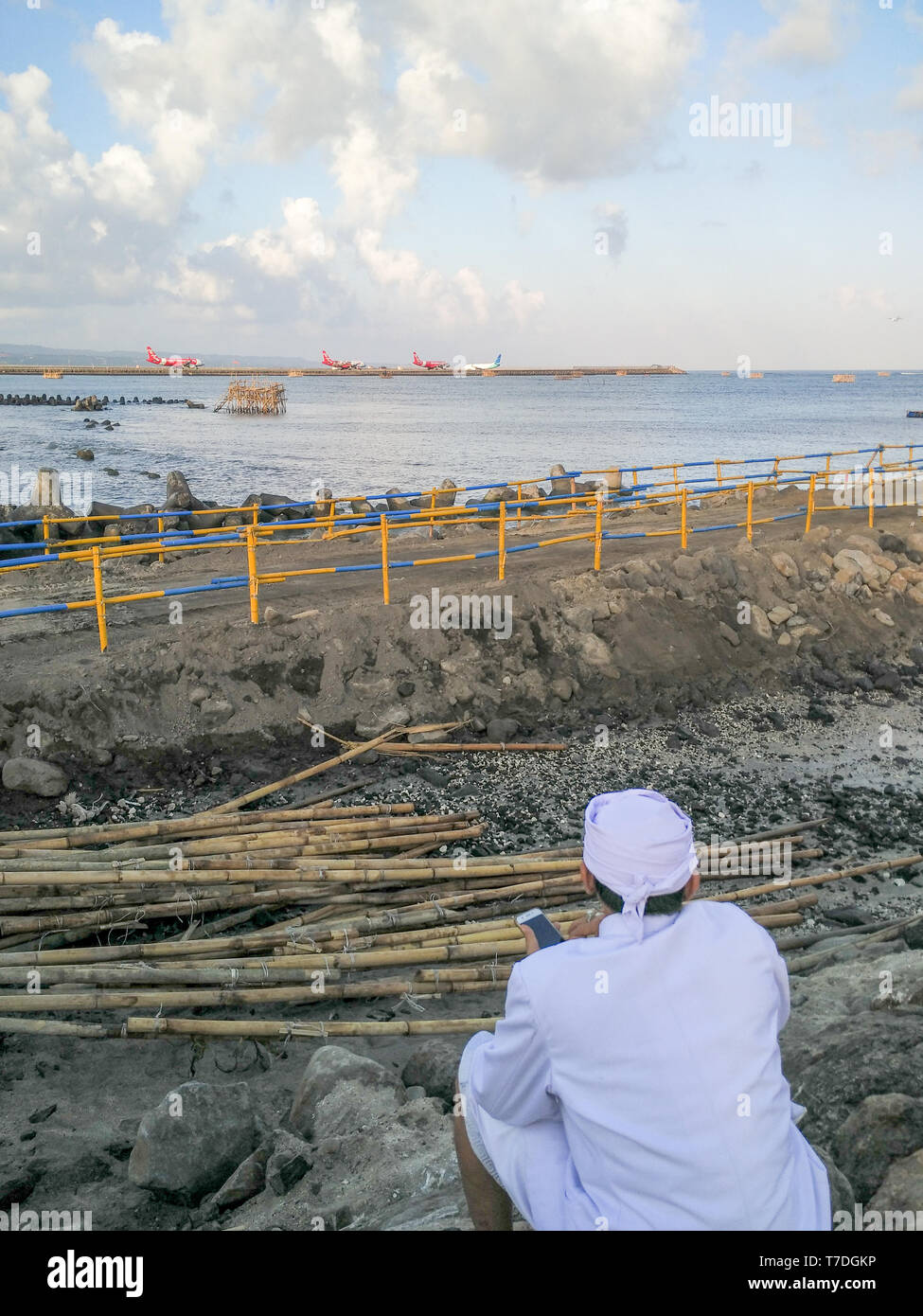 BADUNG BALI - 11. MAI 2018: Ein hinduistischer Priester war, Handy und suchen auf der Baustelle am internationalen Flughafen, wenn die Flugzeuge pr Waren Stockfoto