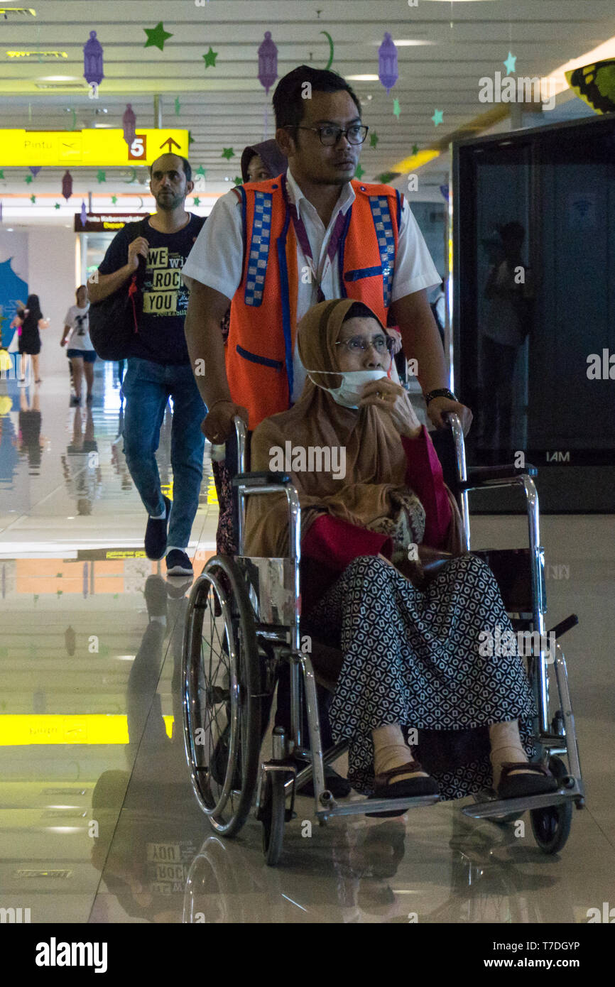 BADUNG BALI - 25. JUNI 2018: Flight Crew hilft kranke Passagiere mit Rollstuhl Stockfoto
