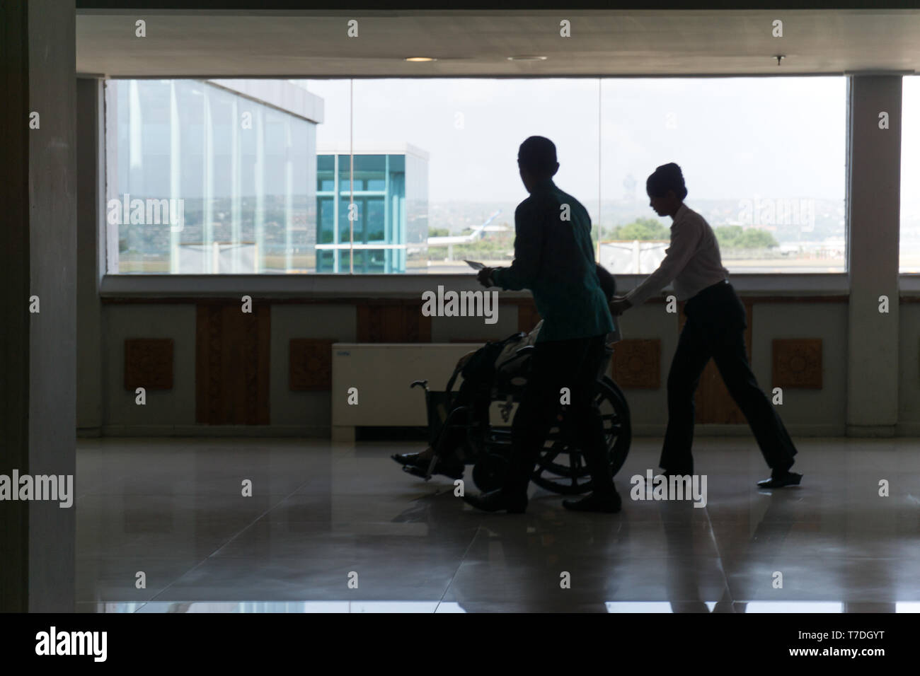 Silhouette der Flugbesatzung hilft kranke Passagiere mit Rollstuhl Stockfoto