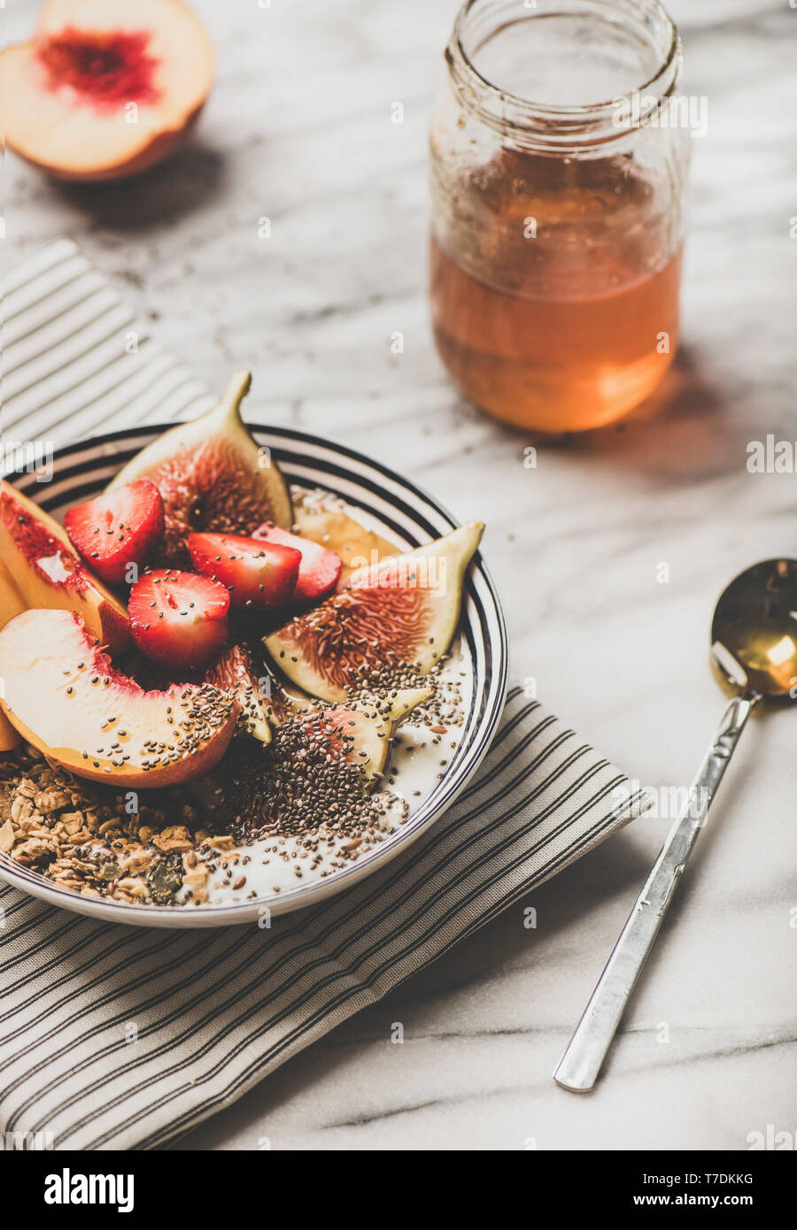 Gesund Sommer Frühstück. Griechischer Joghurt Müsli Schüssel mit Erdbeeren, Feigen, Pfirsich, Chia Samen und Honig mit weißem Marmor Hintergrund. Vegetarisch, d Stockfoto