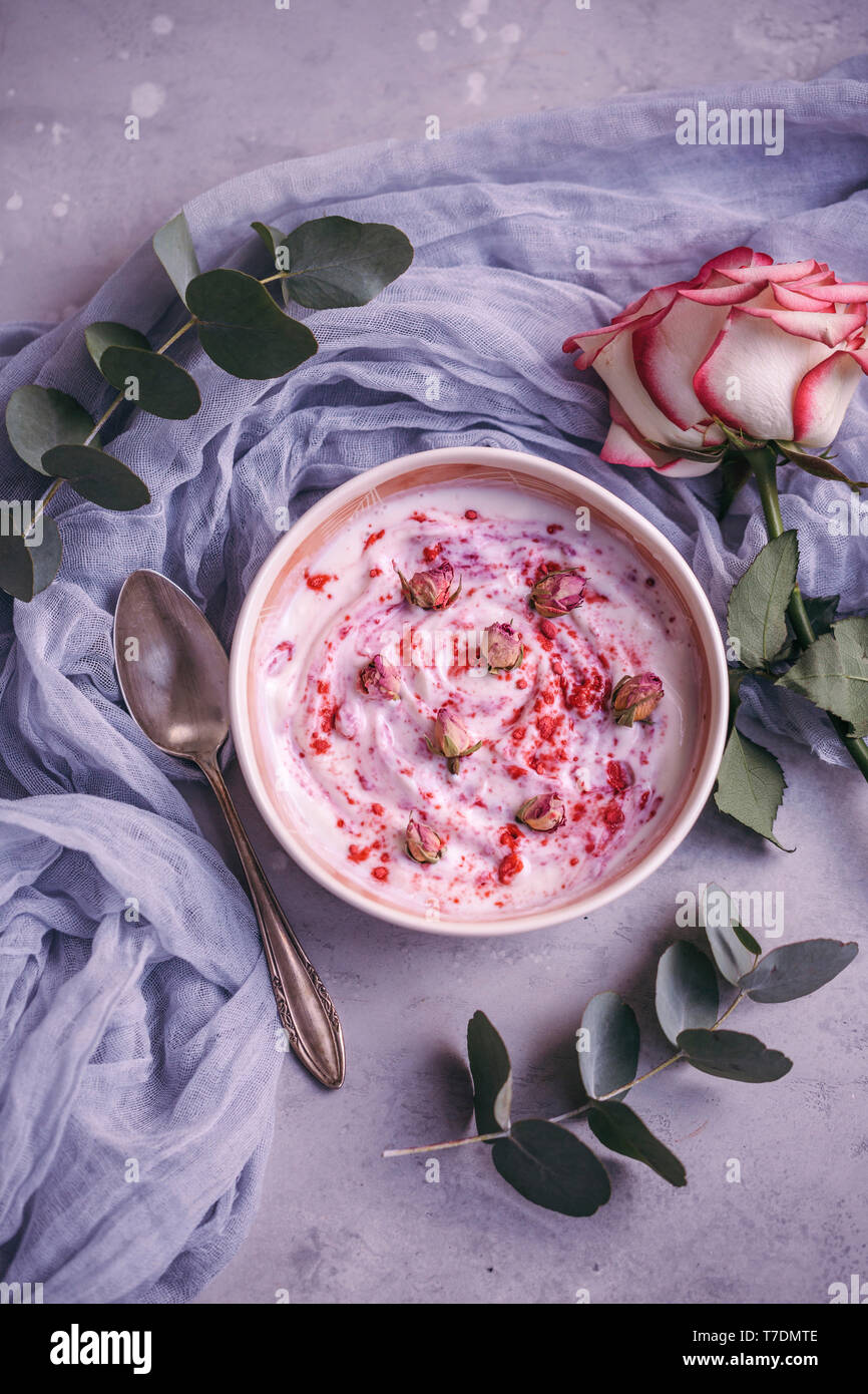 Schüssel mit Joghurt mit Himbeeren Pulver und getrocknete Rosenknospen Stockfoto