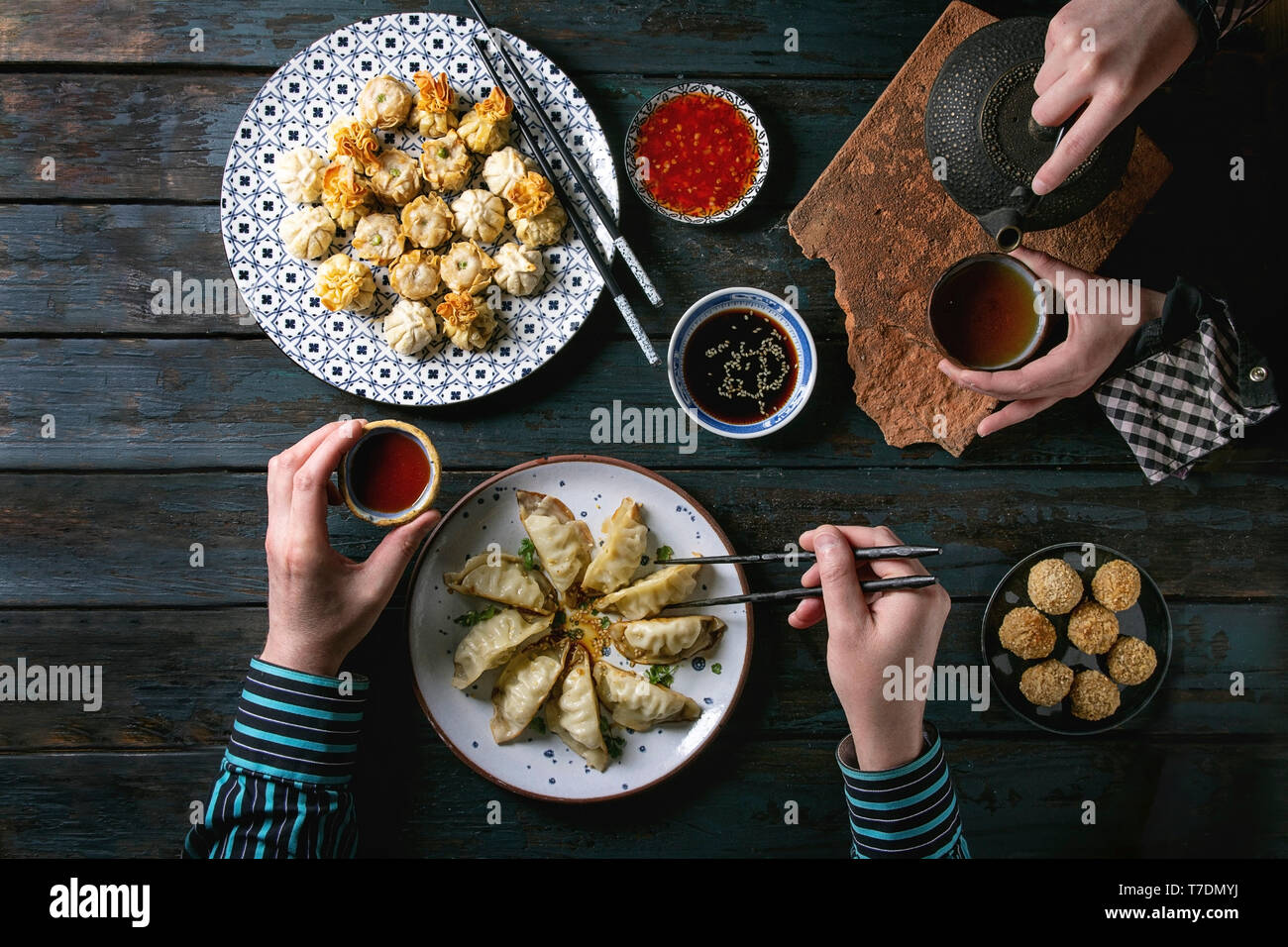 Familie oder Freunden Abendessen mit Dim Sum Gyozas asiatische gebratene Knödel, verschiedenen Saucen in keramischen Platten mit Stäbchen, Kaffee Tassen und teapo serviert. Stockfoto