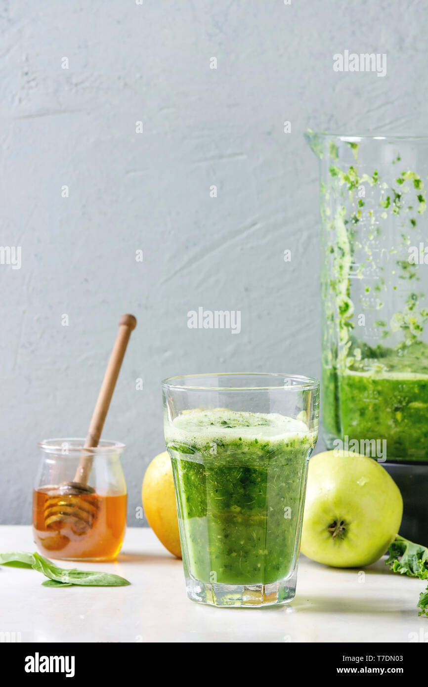 Grüne Spinat kale apple Honig Smoothie in Glas auf weißem Marmortisch mit Blender und Zutaten. Gesunde organische Essen. Stockfoto