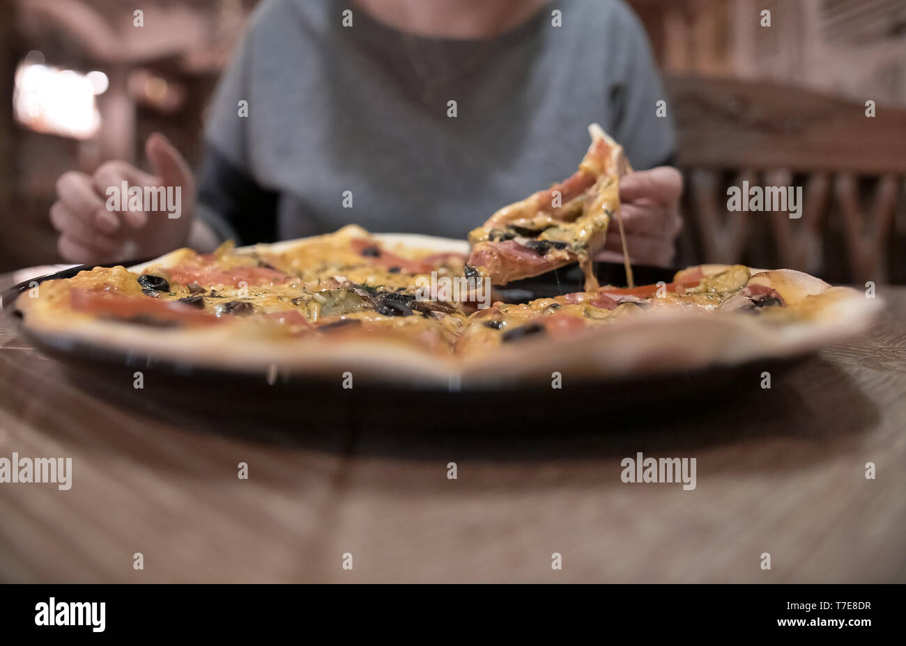 Weibliche Hände mit einem Stück Pizza, verschwommenen Hintergrund Stockfoto