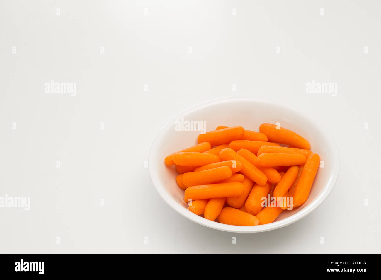 Karotten in Teller auf Weiß. Stockfoto