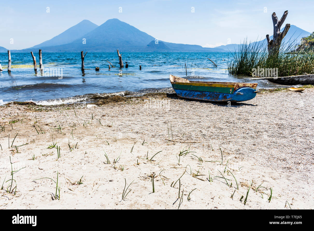 Traditionelle Holz- Boot am Strand mit Toliman & Atitlan Vulkane am Horizont am Atitlan See, Guatemala. Stockfoto
