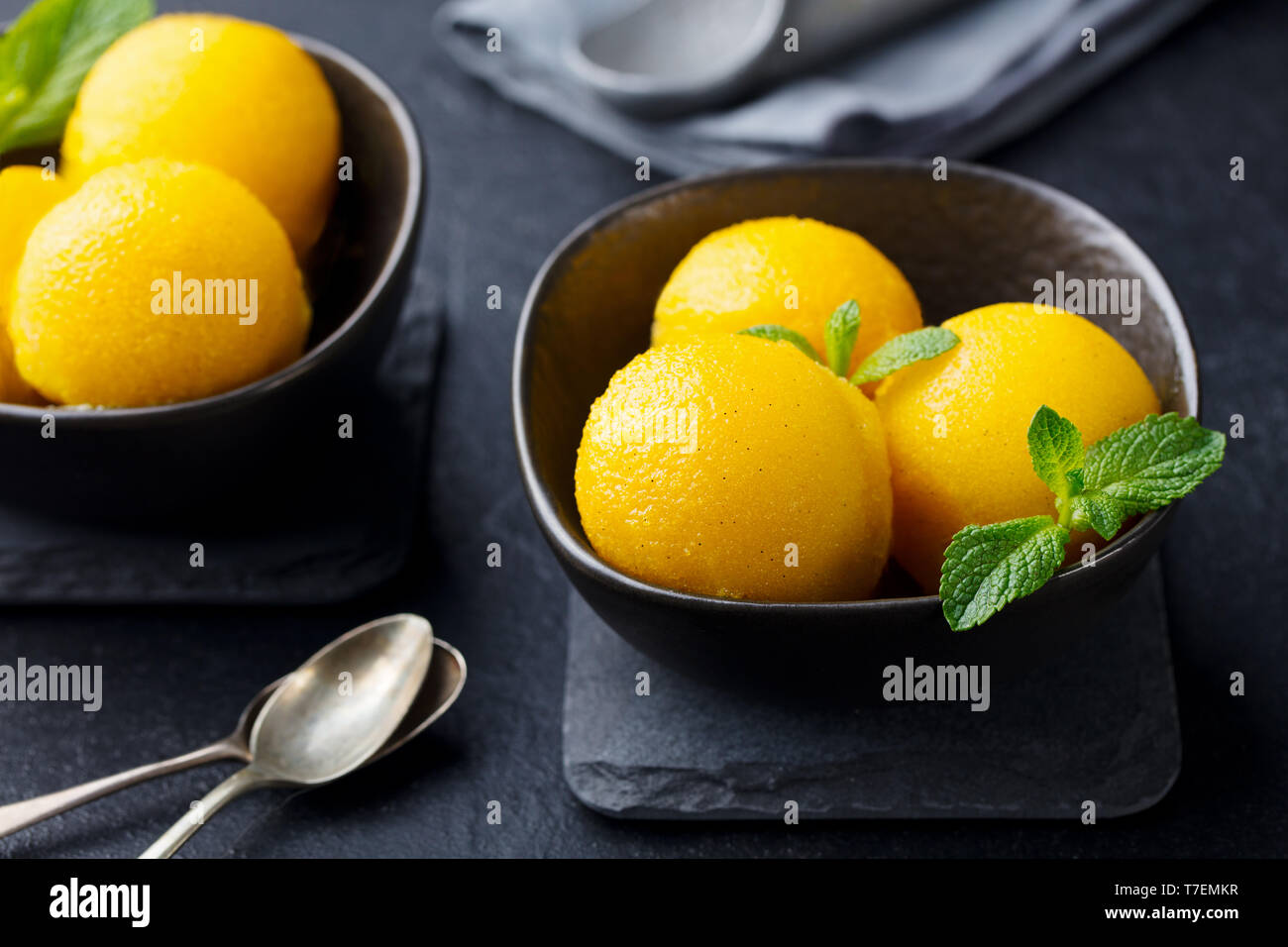 Mango Eis, Tropical Fruit Sorbet in schwarz Schüssel auf schiefer Hintergrund. Close Up. Stockfoto