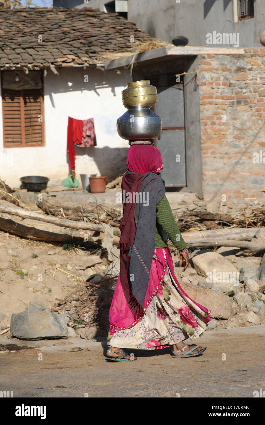 Frau schwer tragen, Wasser Schüssel auf dem Kopf eine "Lange, die Straße zu Ihrer Startseite Stockfoto