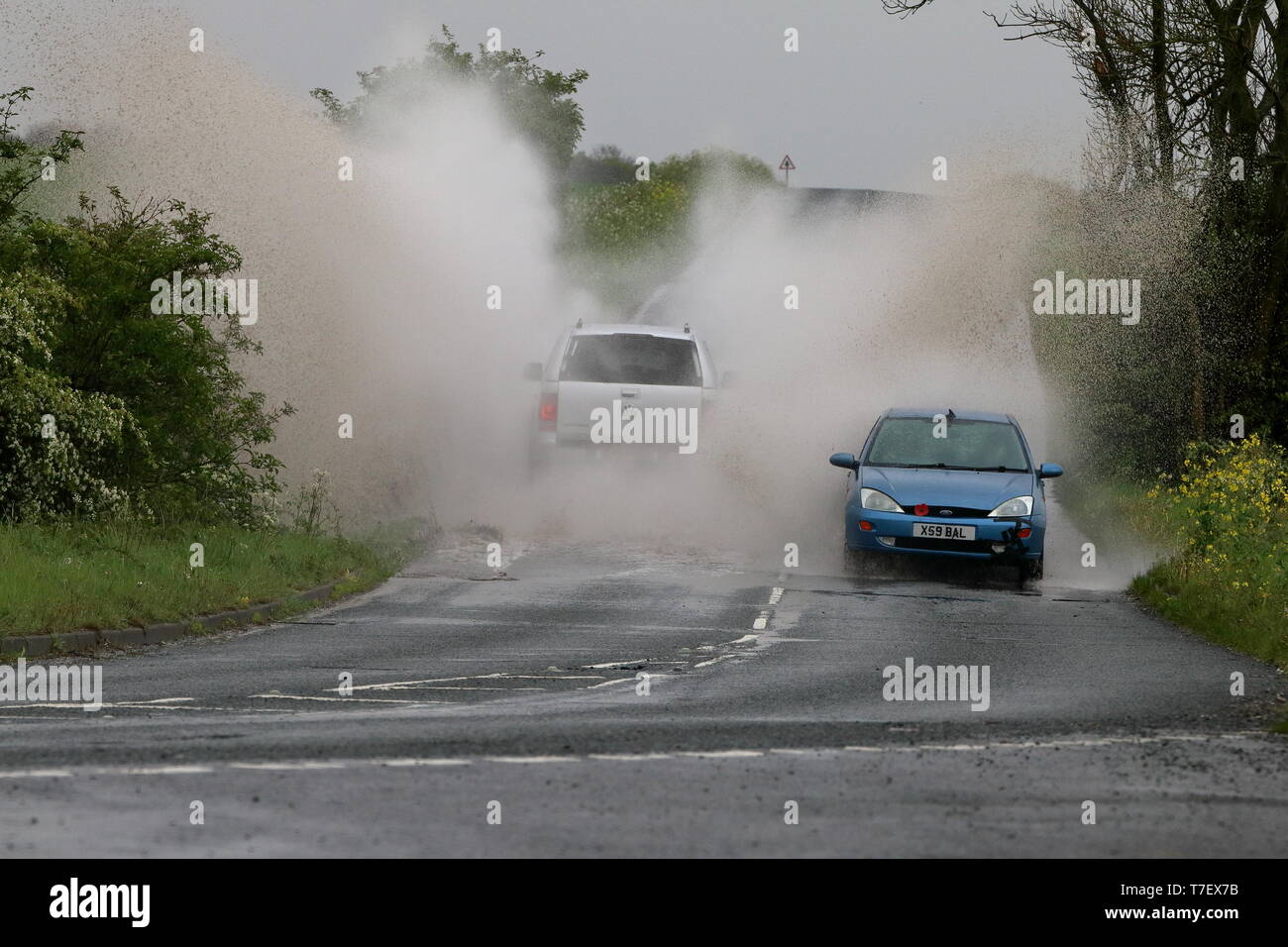 SUV-Spritzer am kommenden Auto, wie es durch eine große Pfütze von Wasser nach starkem Regen geht Stockfoto
