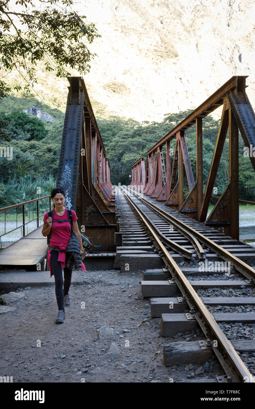 Weißer junge Frau Überquerung der Brücke über den Fluss Urubamba auf der Bahn nach Aguas Calientes und Machu Picchu in Peru Stockfoto