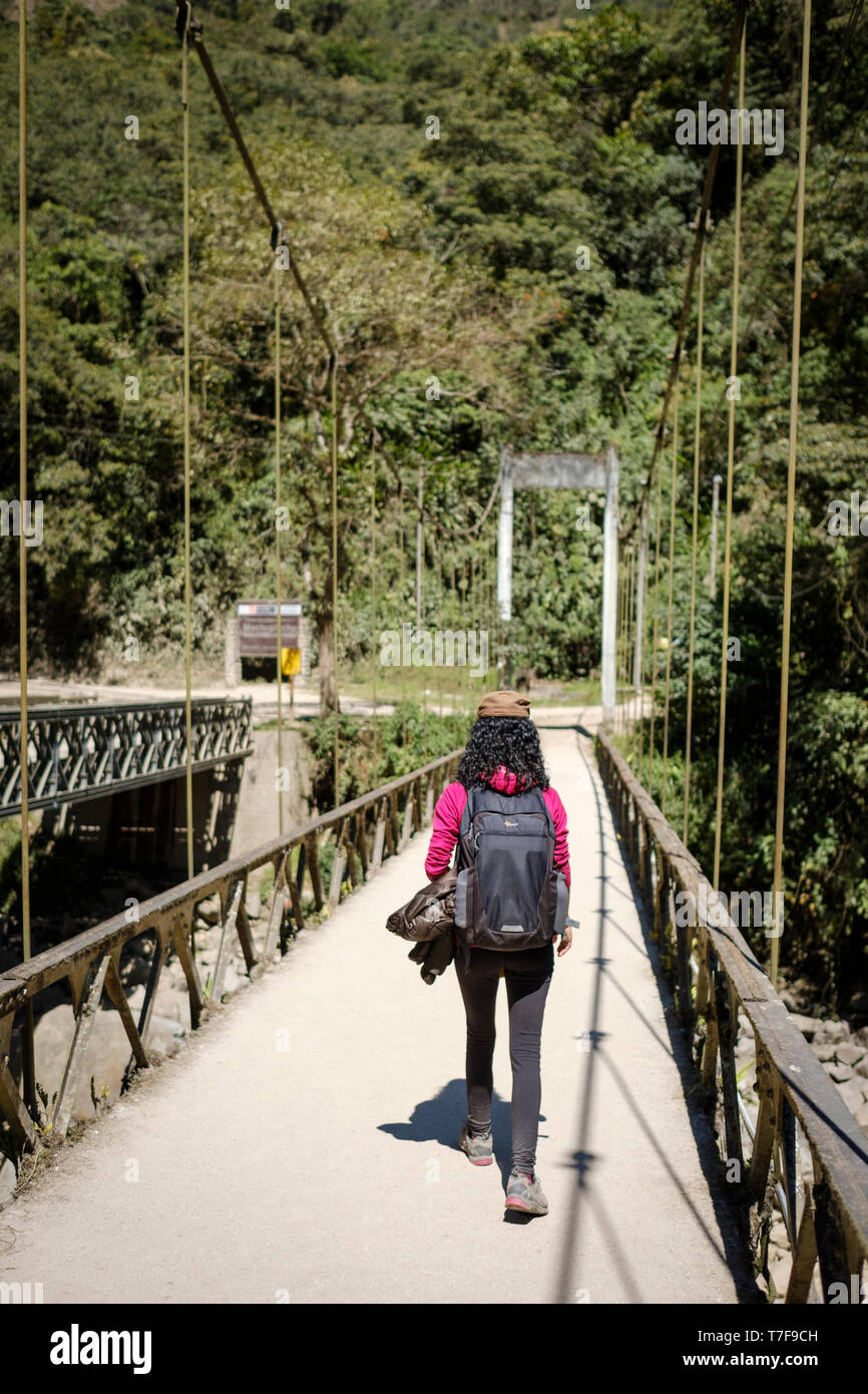 Weiße Frau Touristen auf die Brücke, die das Urubamba Fluss auf dem Weg nach Machu Picchu Ruinen in Peru Kreuze Stockfoto