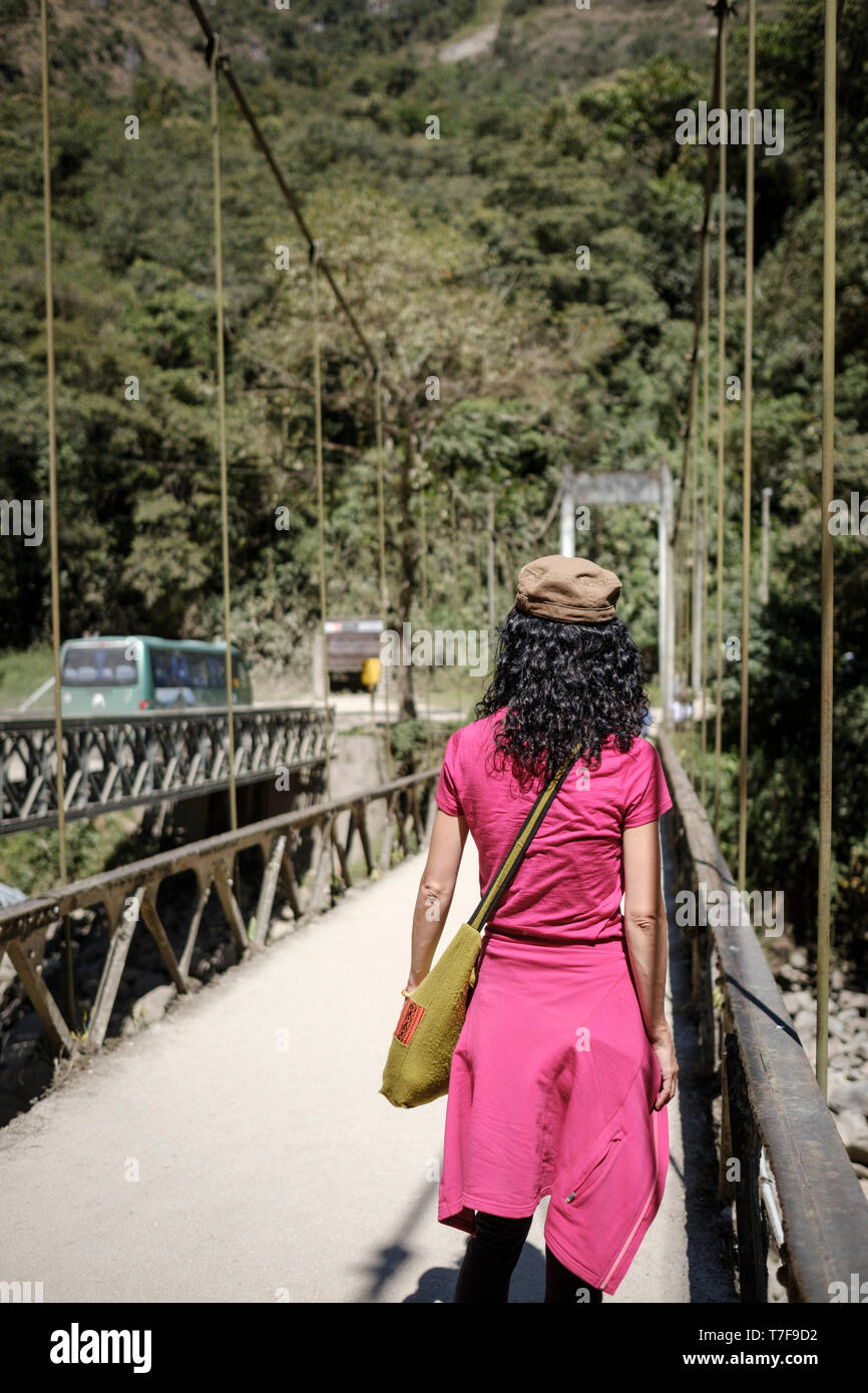 Weiße Frau Touristen auf die Brücke, die das Urubamba Fluss auf dem Weg nach Machu Picchu Ruinen in Peru Kreuze Stockfoto