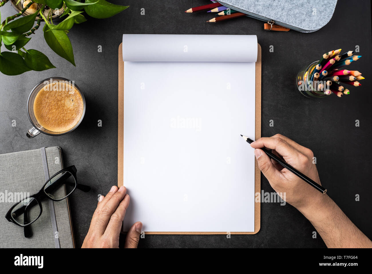 Designkonzept - Ansicht von oben kopieren Raum mit Menschen Hand halten Bleistift, A4 Papier, Topfpflanze, Gläser, Kaffee, Bleistift auf schwarzen Hintergrund für mockup. rea Stockfoto