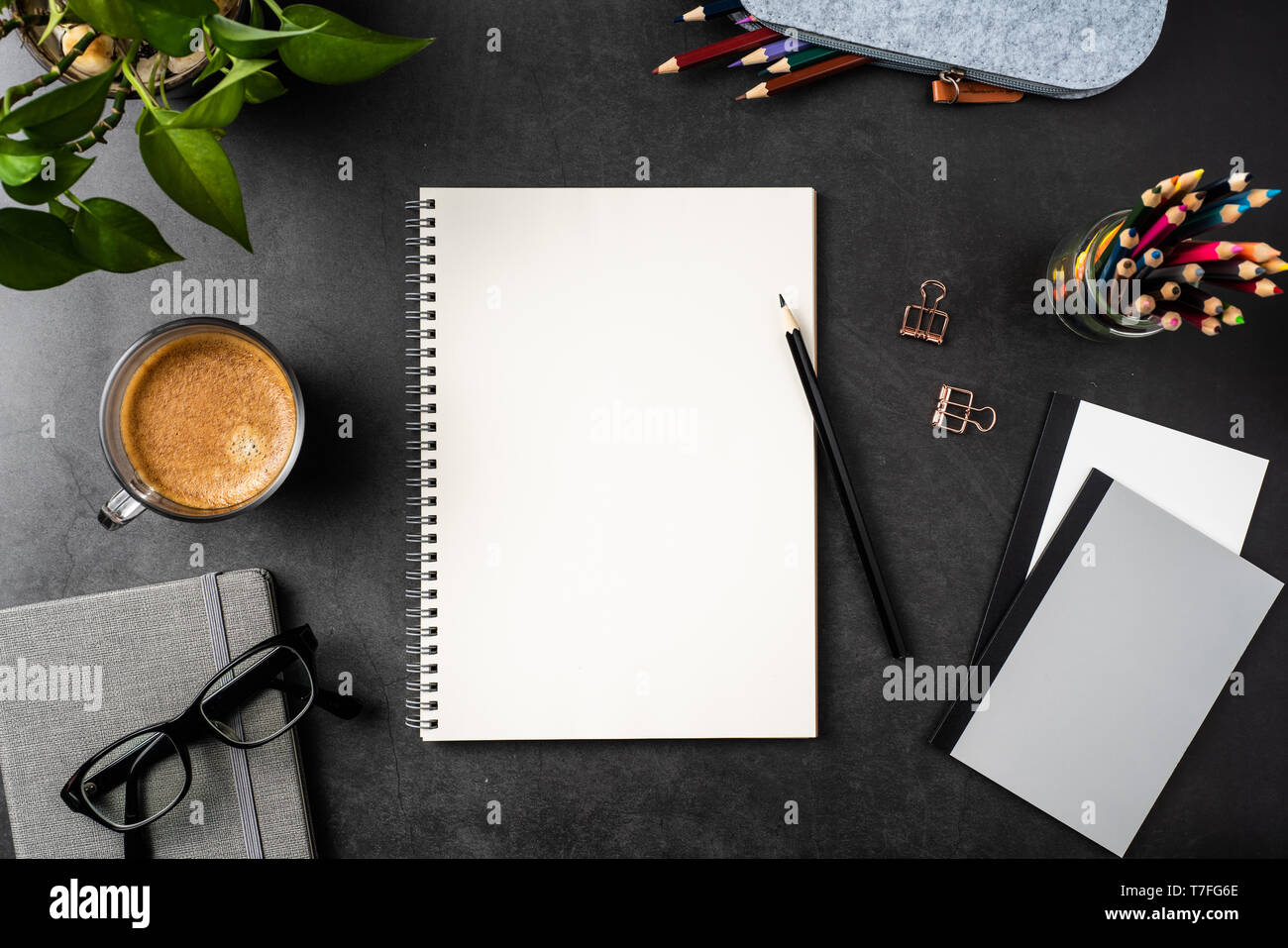 Designkonzept - Ansicht von oben kopieren Raum mit Spirale notebook, Topfpflanze, Gläser, Kaffee, Bleistift auf schwarzen Hintergrund für mockup. echte Fotos und nicht für 3D Stockfoto